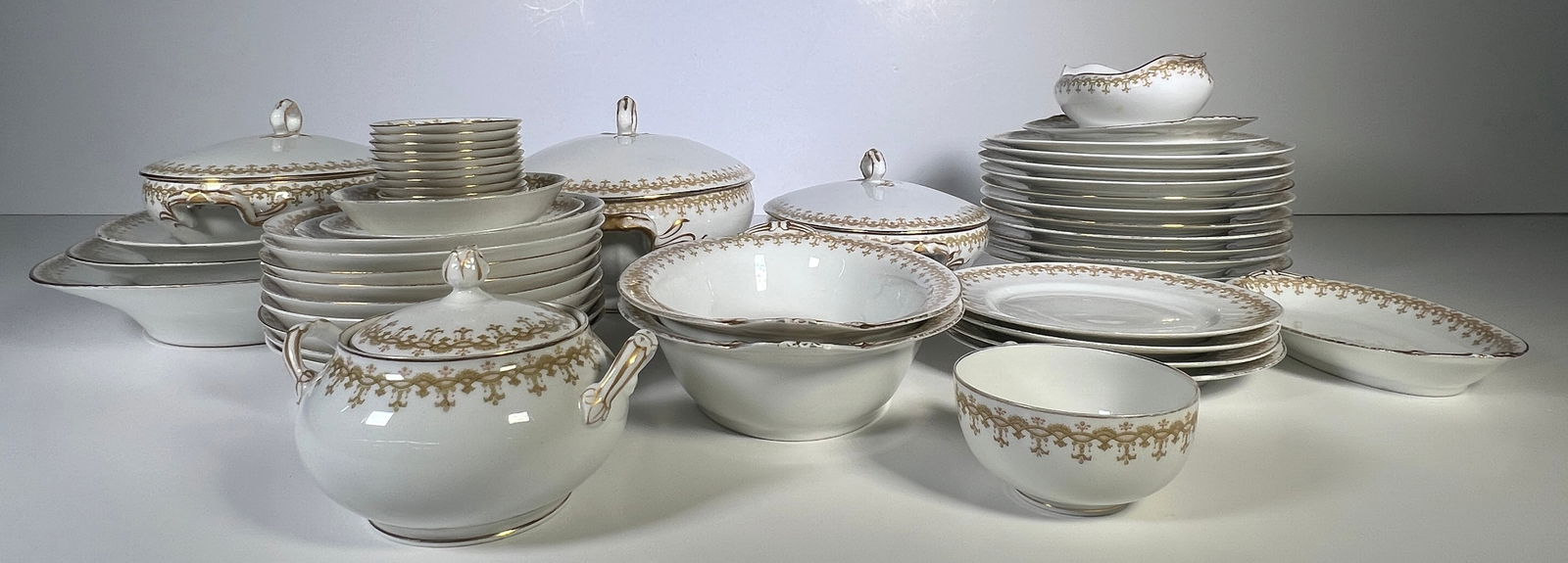Tilden Thurber & Co. Porcelain Dinner Service: Extensive Tilden Thurber & Co. porcelain dinner service. White with gilt floral decoration. Includes various plates, bowls, serving dishes, and covered tureens. Largest item is 13 inches wide, sma