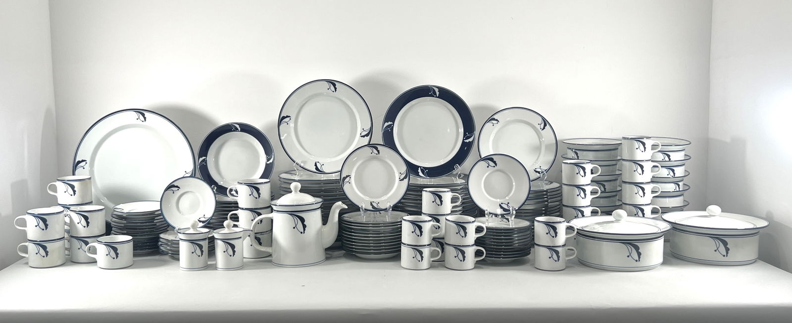 Extensive Dansk Flora Dinnerware Set: Extensive Dansk Flora dinnerware set featuring a white base with a blue floral design. Includes plates, bowls, cups, saucers, teapot, and serving dishes. A complete set for elegant dining.