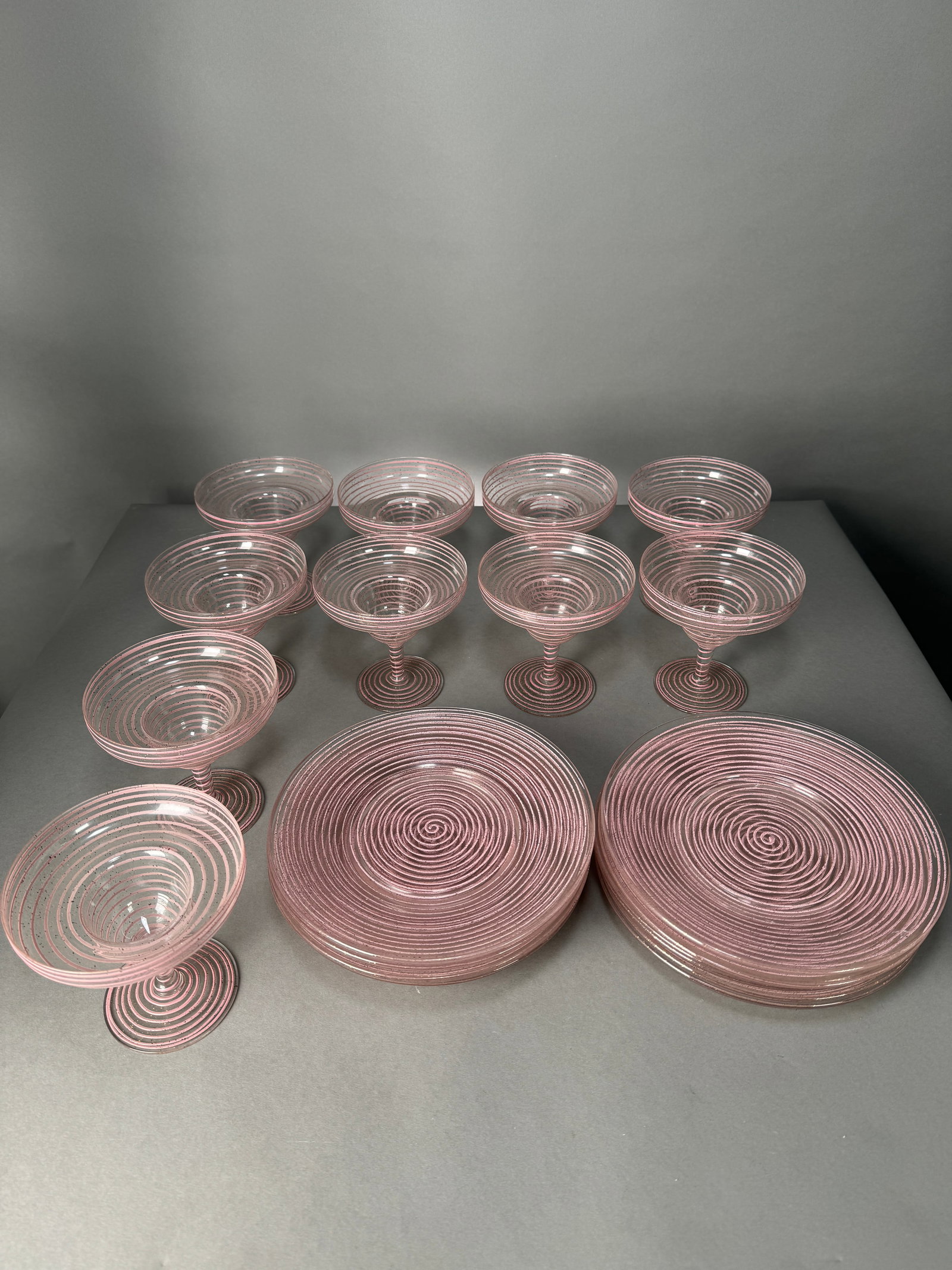 Set of 22 Mid-Century Pink Spiral Glassware: Set of 22 pieces of vintage glassware featuring a pink spiral design. Includes plates (8" diameter) and glasses (4.75" tall, 4.5" diameter at top). 