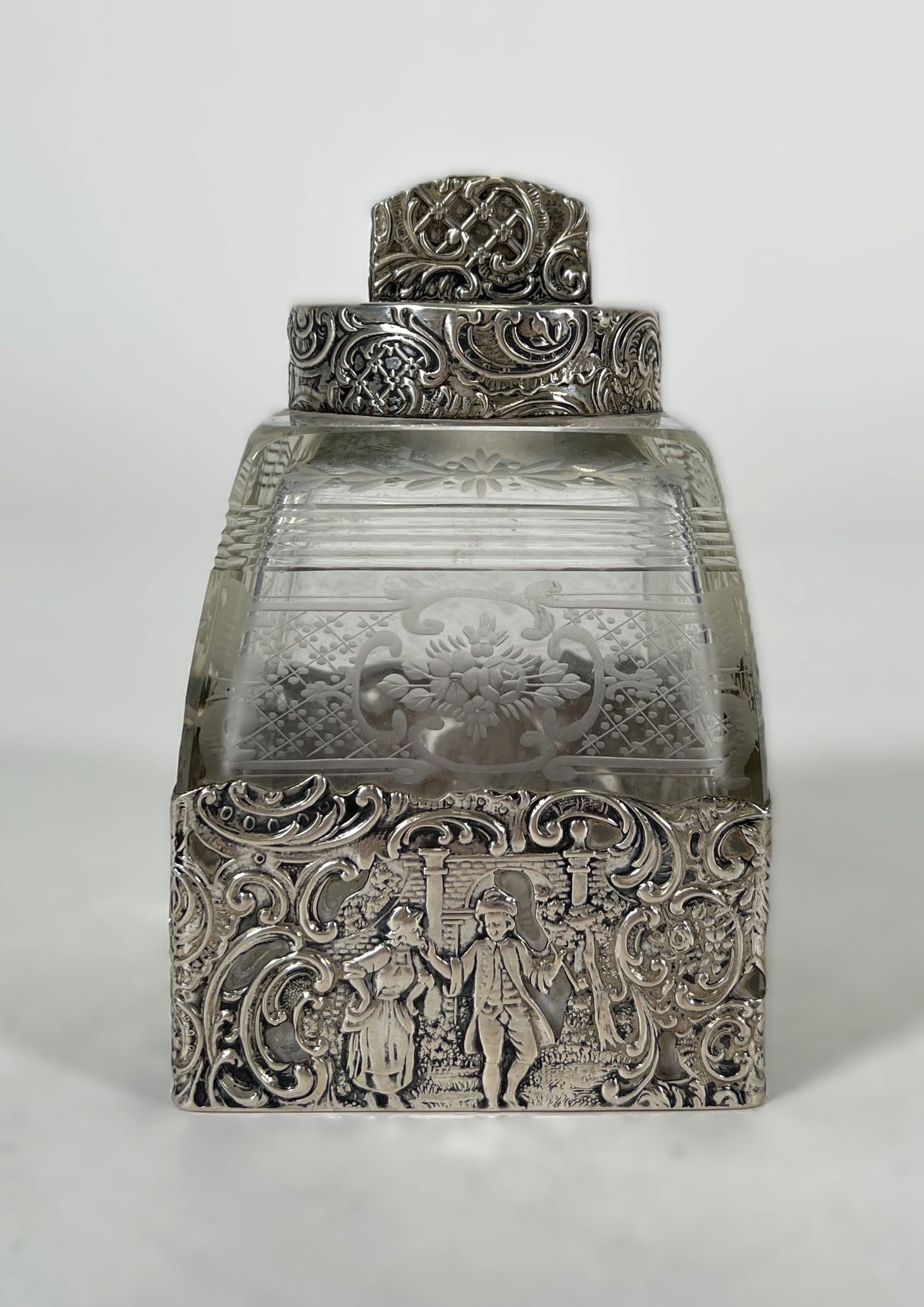 Sterling Silver & Crystal Dresser Jar with Figural Scene: Sterling silver and cut crystal dresser jar. The sterling base and lid feature ornate foliate designs and a figural scene. Hallmarks are present but illegible. Notable crack through glass.