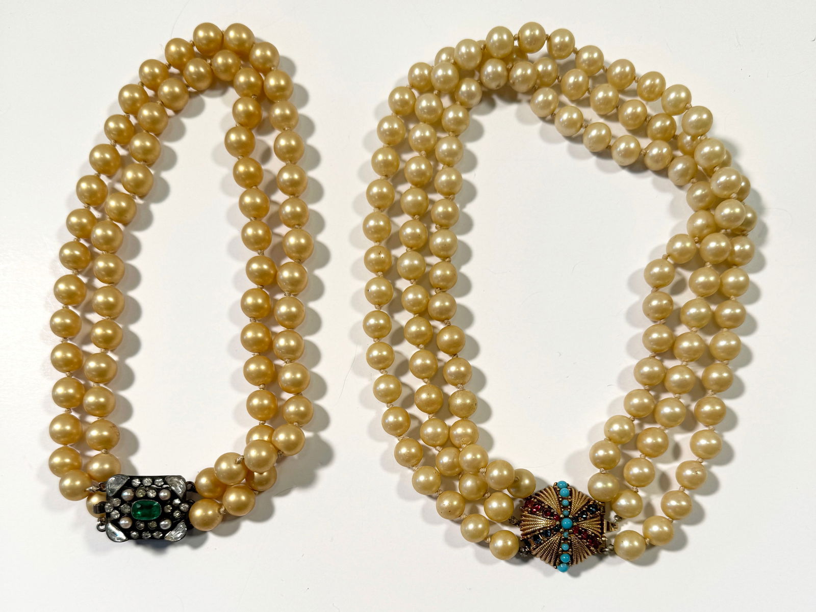 Two Ciner Faux Pearl Necklaces: Two vintage Ciner faux pearl necklaces. One is a double strand with a silver-tone clasp featuring an emerald-colored stone and clear rhinestones. The other is a triple strand with a gold-tone clasp