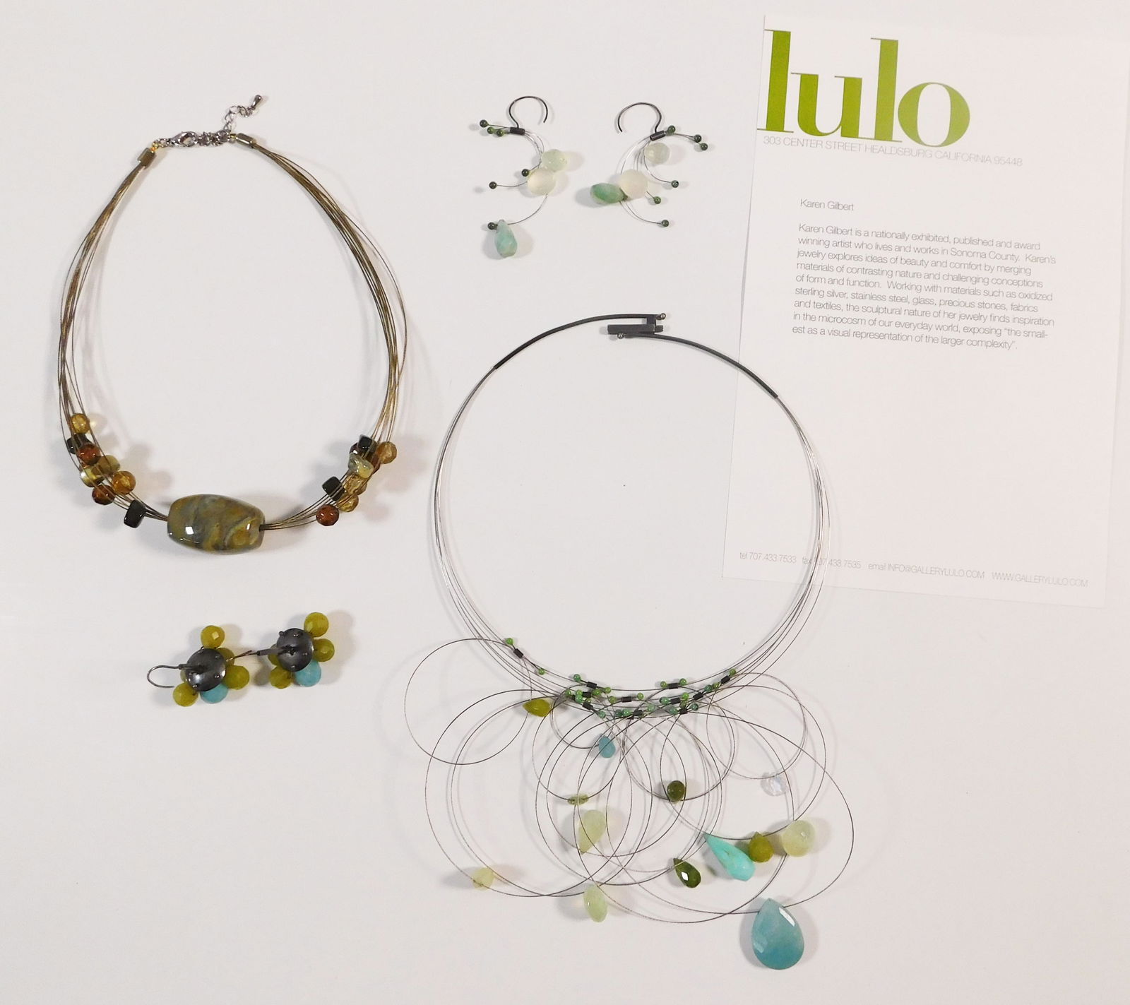 Karen Gilbert Jewelry: A set of Lulo jewelry by Karen Gilbert featuring two necklaces and two pairs of earrings. The necklaces are beaded and strung on wire. One pair of earrings features a cluster design, while the