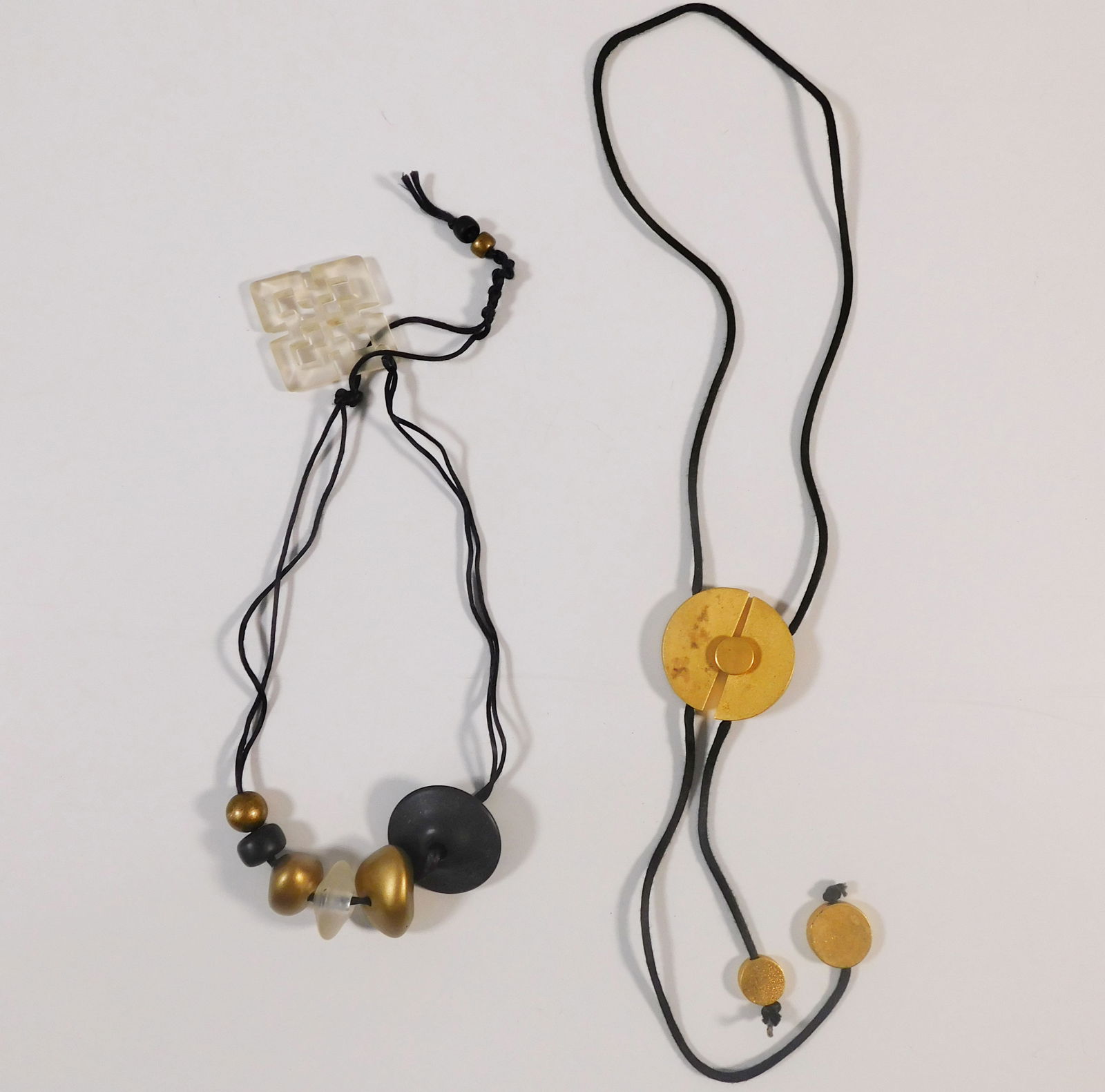 Two Necklaces: Two necklaces. One is a beaded necklace with black cord and various beads. The other is a bolo-style necklace with a gold-tone metal slide and black cord. Total weight: 85g. Longest item is 36.5