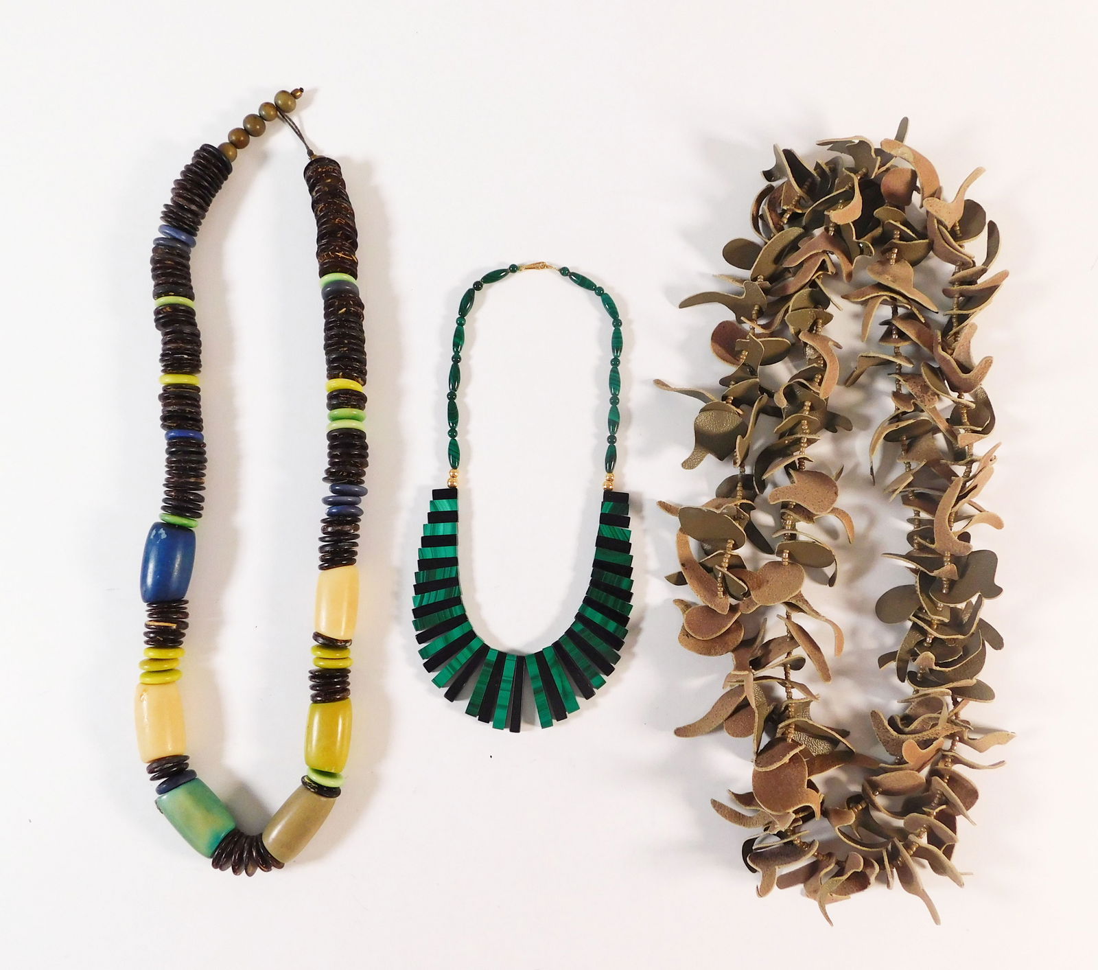 Three Necklaces: Three costume necklaces, including one with large colored beads, one with green and black segments, and one made of organic material. Largest item measures 21.5 inches. Total weight: 226.8g