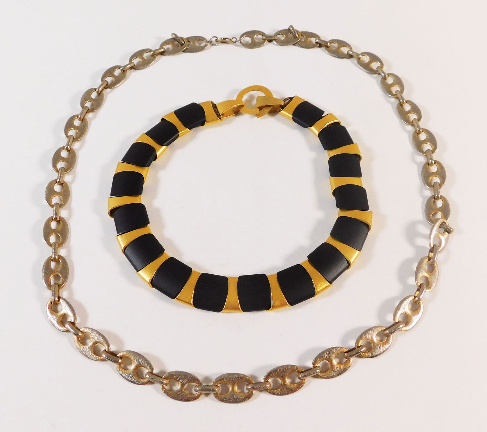 Two Necklaces: Two costume necklaces. One is a gold-tone chain necklace, the other is a black and gold-tone necklace. The chain necklace is approximately 30 inches long. Total weight: 226.8g