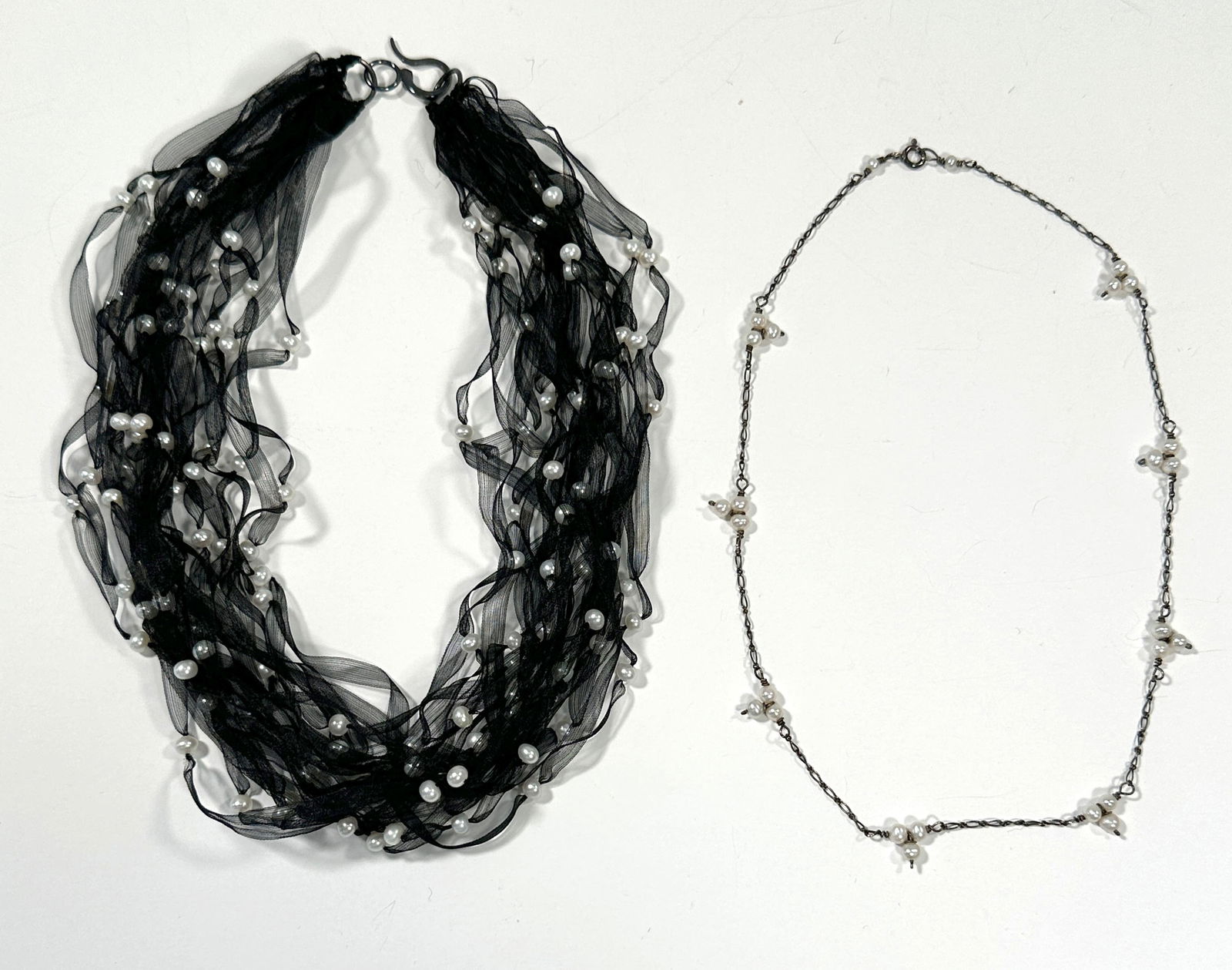 Two Sterling Silver & Pearl Necklaces: Two necklaces featuring pearls and sterling silver. One is a black ribbon necklace with scattered pearls. The other is a chain necklace with pearl clusters. 22geach 16"