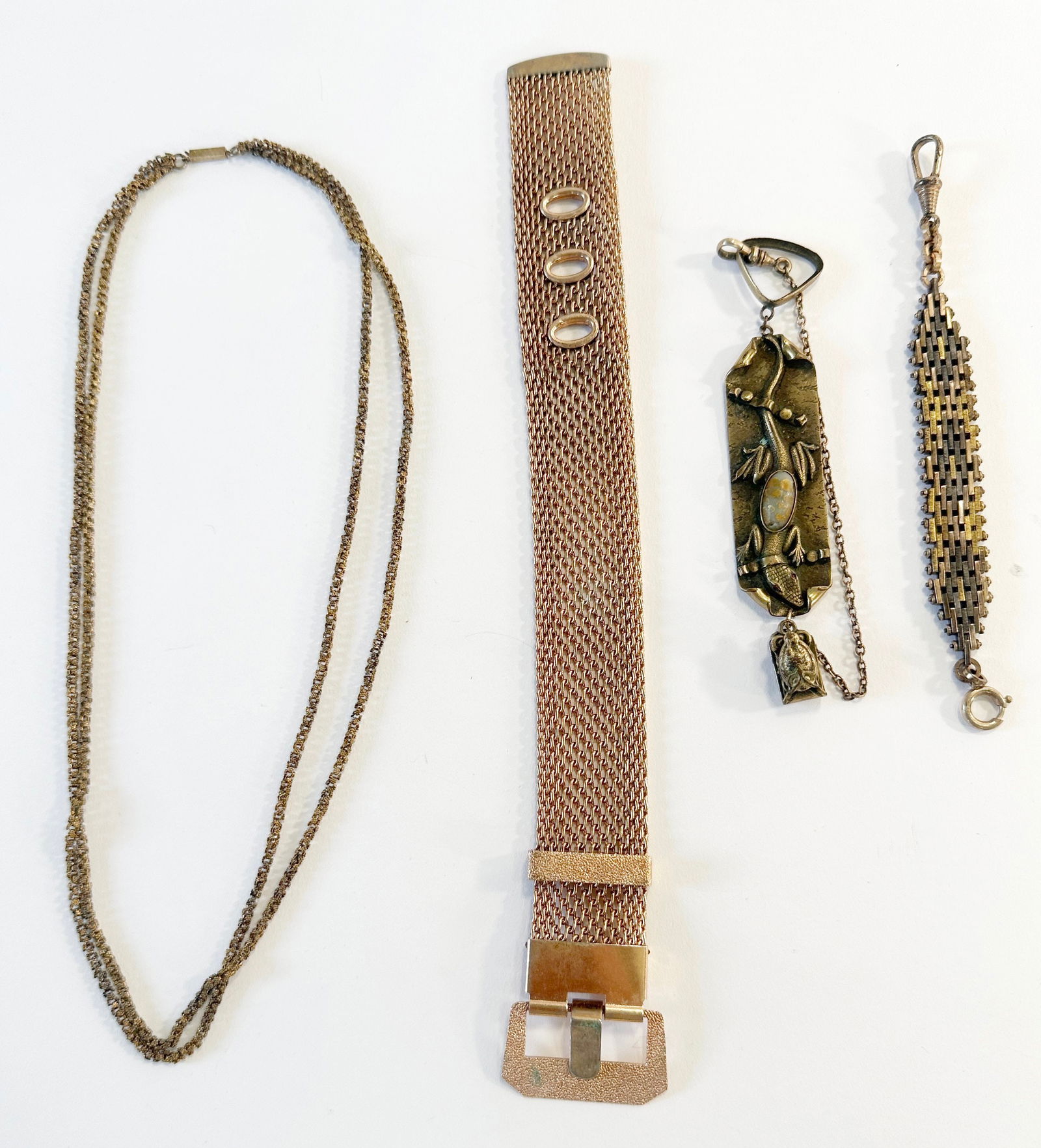 Gold Tone Jewelry Assortment: A collection of costume jewelry including a long double-strand necklace with floral chain links, a rose gold tone mesh bracelet, and two watch fobs. One fob is unmarked and the other is a George N.