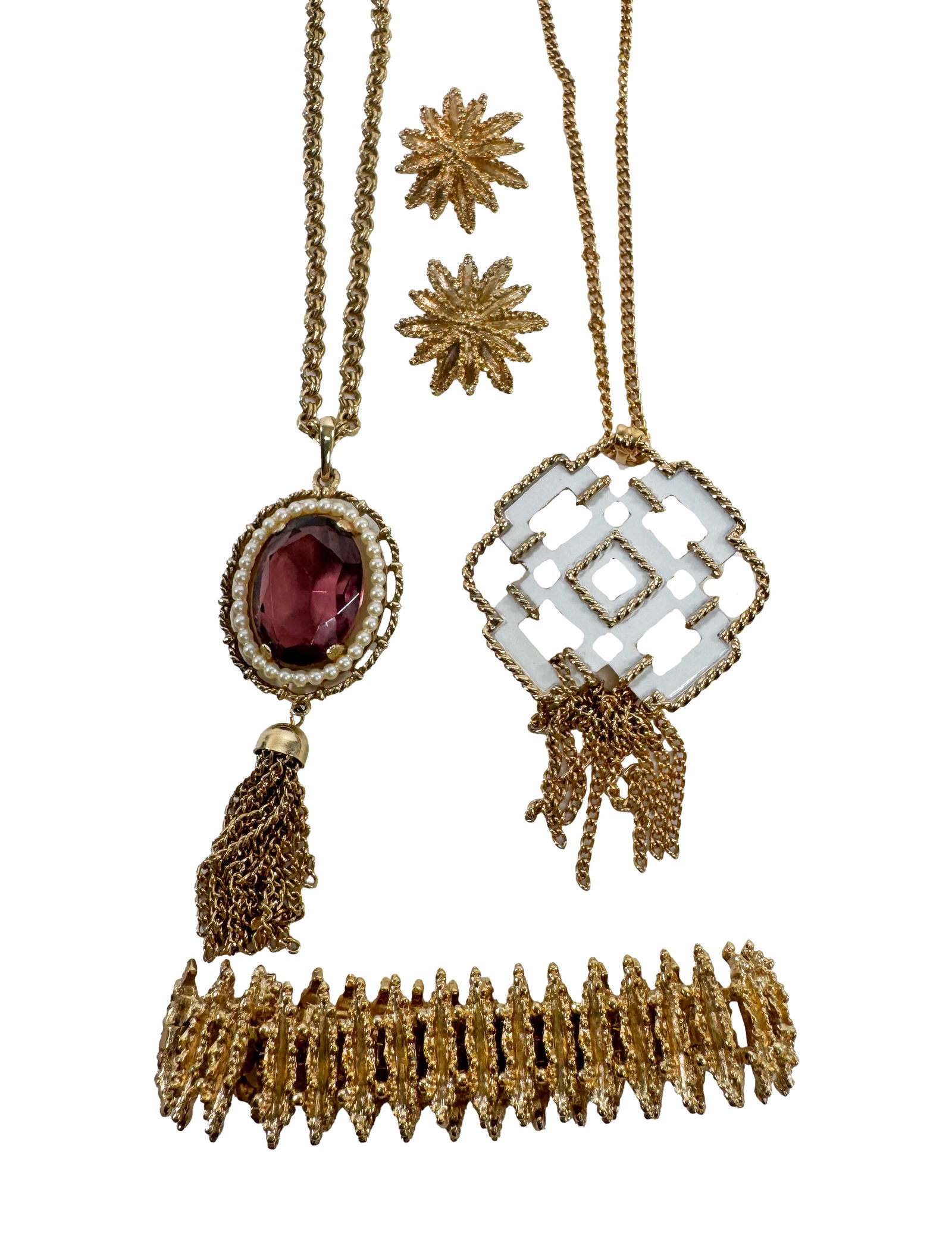Avon Gold Tone Jewelry Group: Avon gold tone jewelry group. Includes two necklaces, a bracelet, and a pair of earrings. One necklace features a white geometric pendant, the other a faux amethyst pendant.Weight: 130.4g