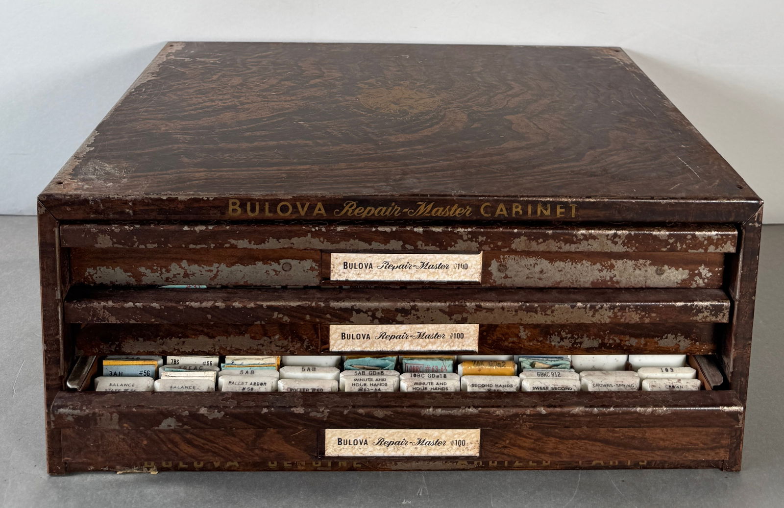 Vintage Bulova Repair-Master Cabinet with Watch Parts: Vintage Bulova Repair-Master Cabinet with three drawers. Contains various types of vintage watch parts for repair. Measures approximately 5.75 x 13 inches and weighs 20.113 lbs.