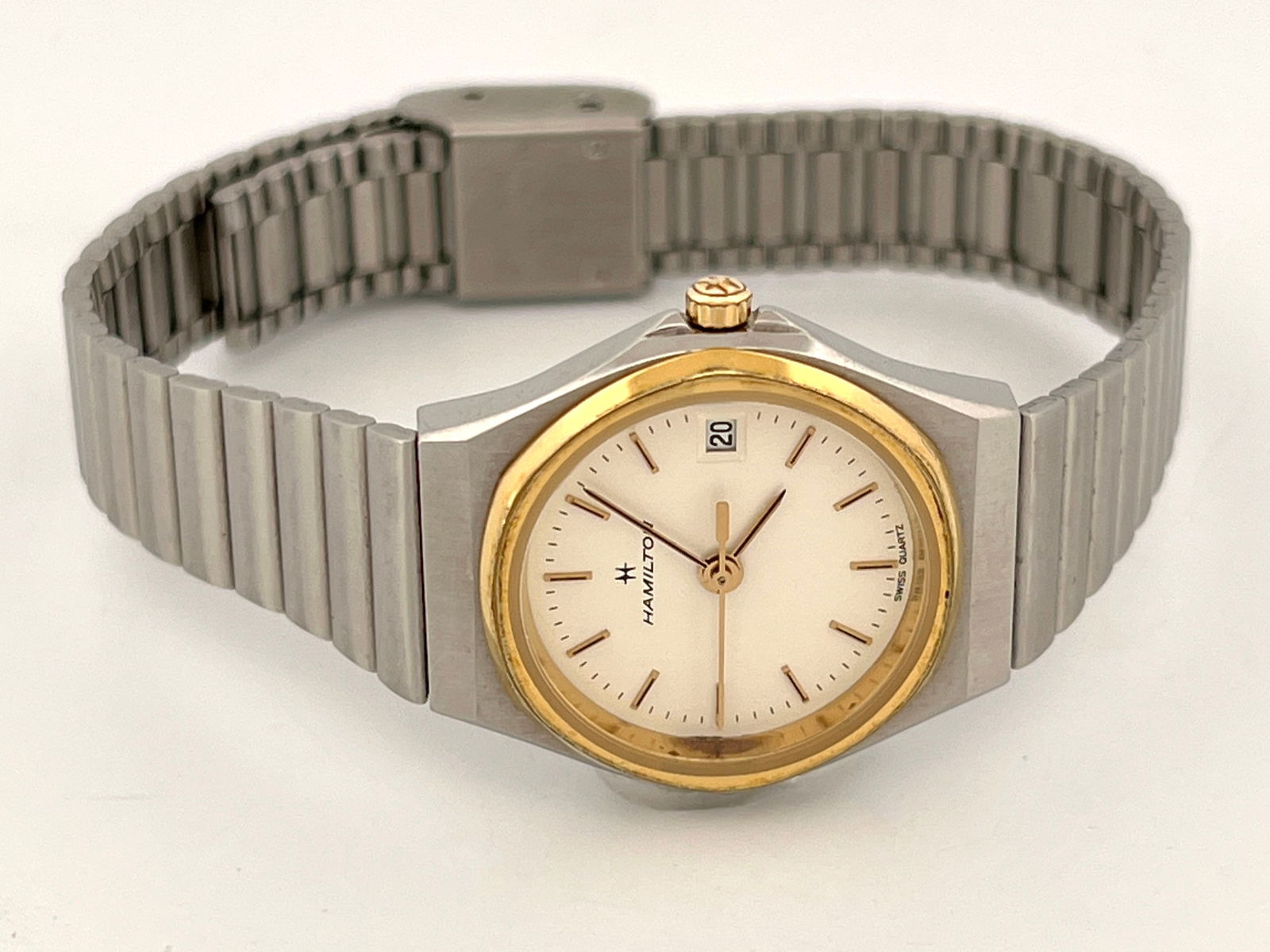 Hamilton 8608 Stainless Steel Wristwatch: Hamilton wristwatch, model 8608. Features a stainless steel case and band with gold-tone hands, indices, bezel, and crown. The dial is off-white with black lettering "Hamilton" and &quo