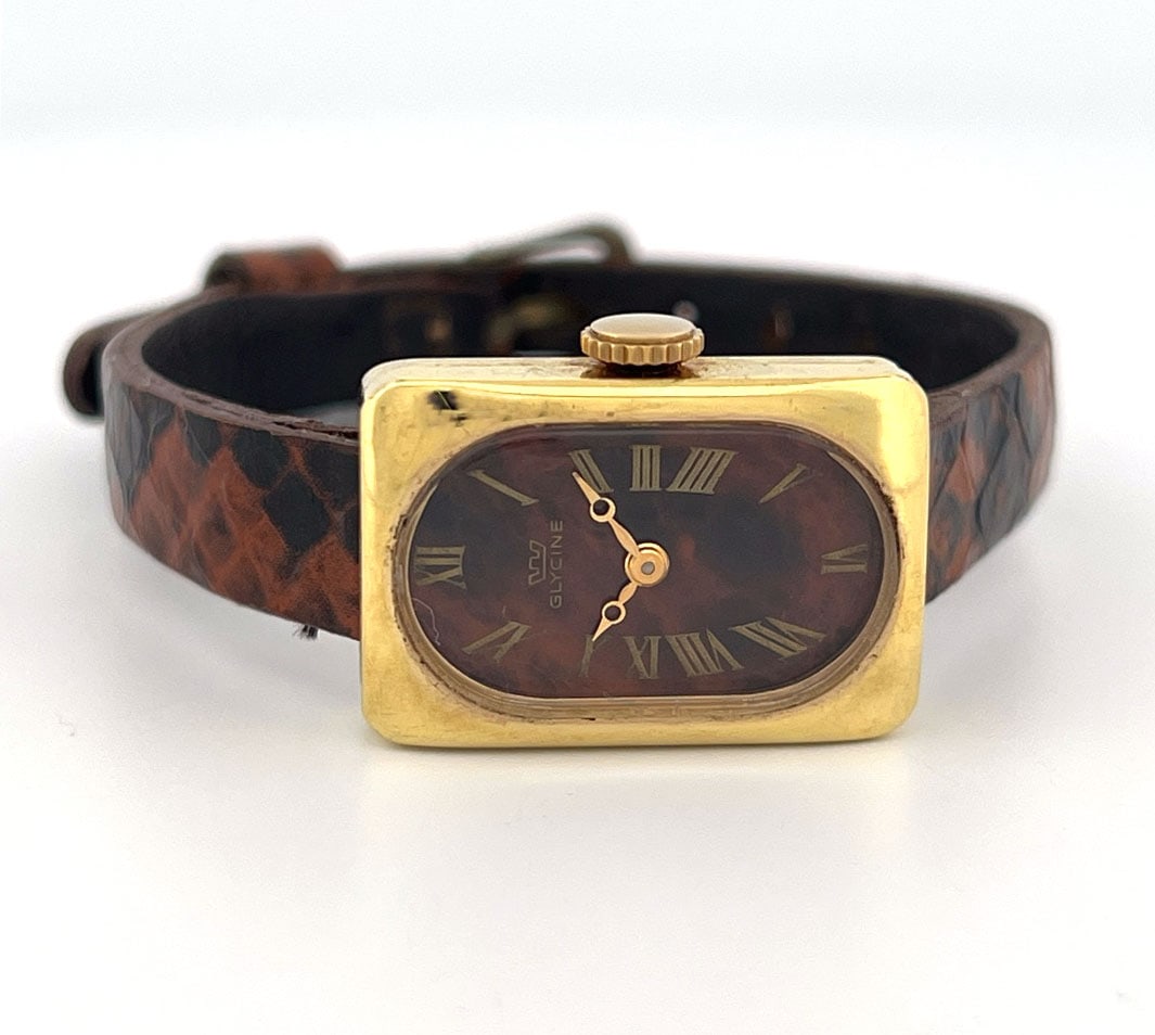 Vintage Glycine Gold Electroplated Wristwatch: Vintage Glycine wristwatch. Gold electroplated case with brown dial and Roman numeral markers. Swiss made, shock resistant. Comes with a brown snakeskin-patterned leather strap.
