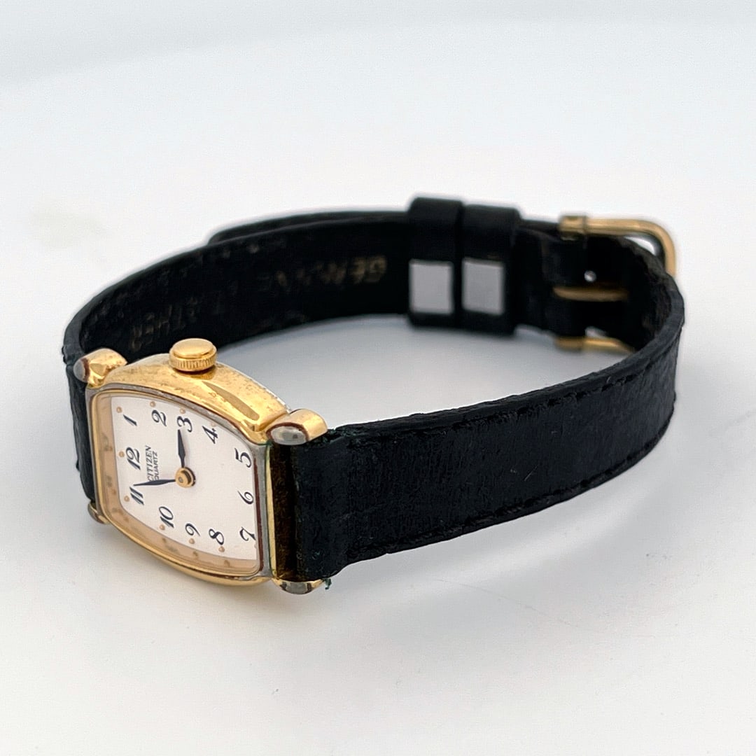 Citizen Quartz Ladies Wristwatch with Black Leather Band: Citizen Quartz wristwatch with a gold-tone case and a white dial with black numerals. The watch features a black leather band and is marked 'Citizen' on the dial. The back of the case indicate