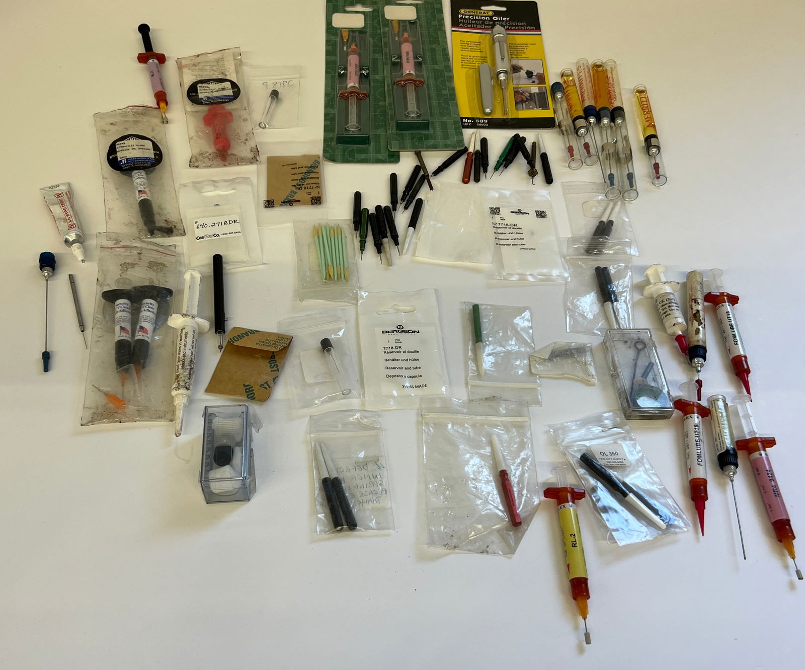 Watch Oiling Tools and Crystal Adhesive: A collection of watch oiling tools and crystal adhesive. Includes various oilers, applicators, lubricants, adhesive tubes, spare parts. An assortment of tools for watch maintenance and repair.