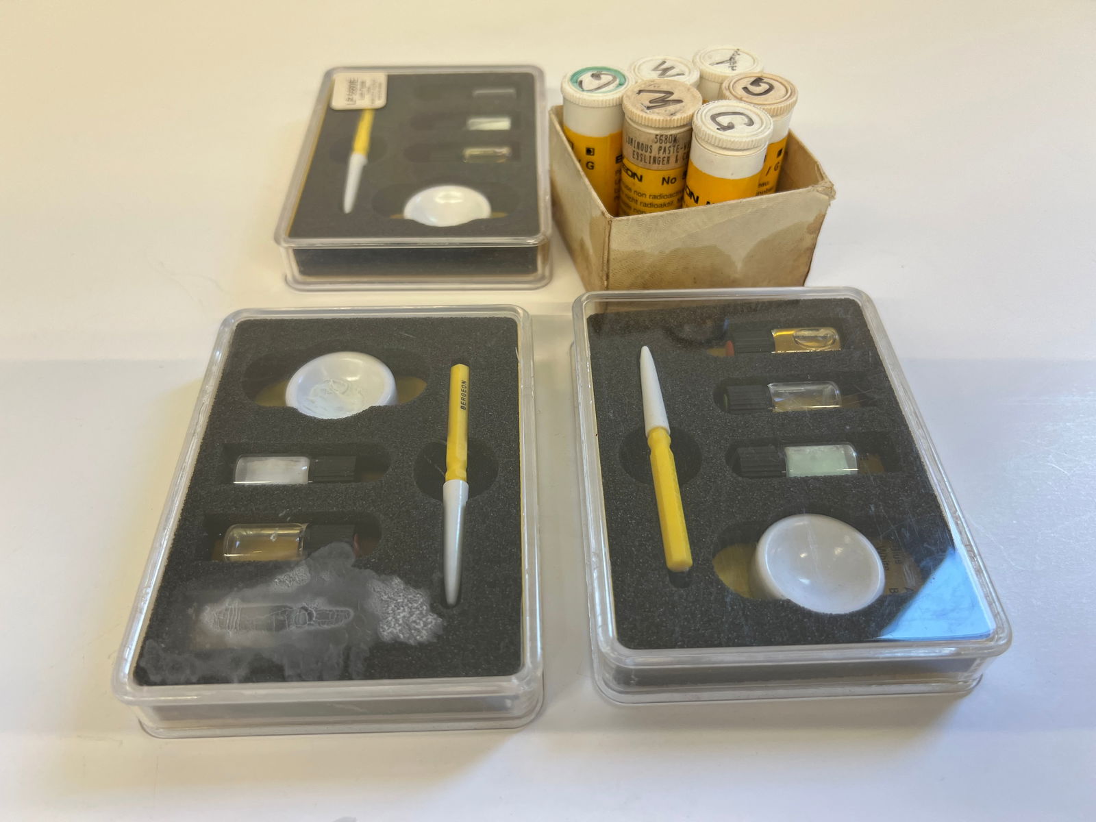 Bergeon Luminous Paste and Tools: A collection of Bergeon luminous paste and application tools. Includes multiple containers of luminous paste in various colors, application tools, and mixing bowls. For watch repair and restoration.