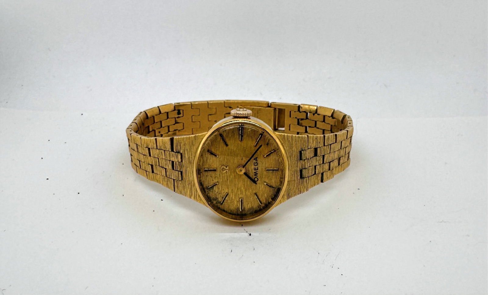 Vintage Omega Gold Plated Ladies Wristwatch: Vintage Omega ladies wristwatch with a gold plated finish and textured gold tone band. The movement is marked Omega Swiss 17 Jewels. The band is marked 20 Microns Gold Plated Top, Stainless Steel