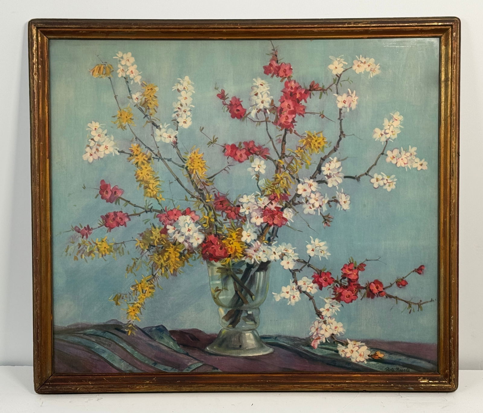 Still Life Painting by Rolf Regele: Floral still life painting featuring an arrangement of colorful blossoms in a glass vase, set against a blue background with a draped cloth. Framed.