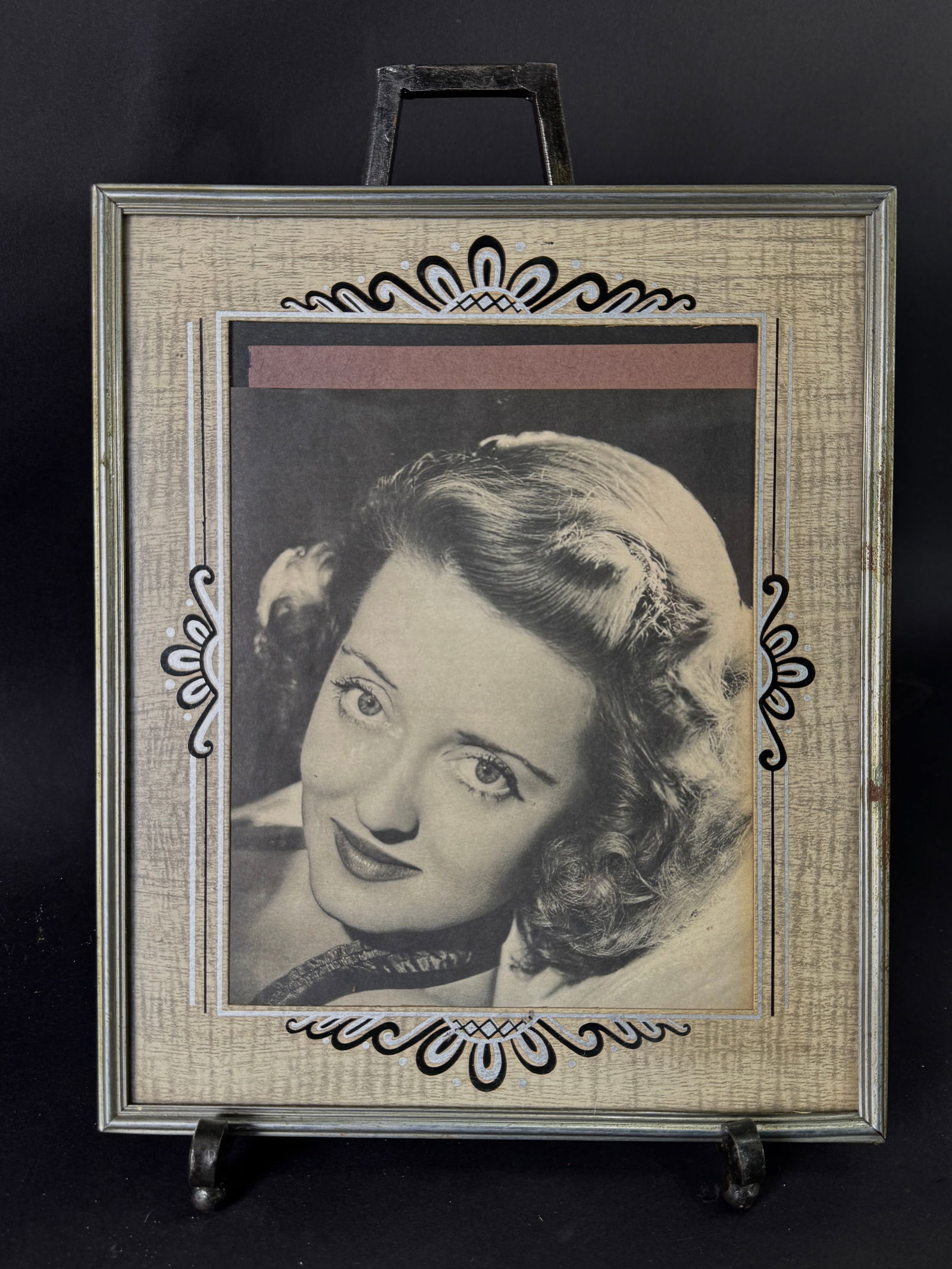 Framed Portrait of Bette Davis: Framed black and white portrait of Bette Davis. The image is set within a decorative frame. Dimensions: 12 x 10 inches.