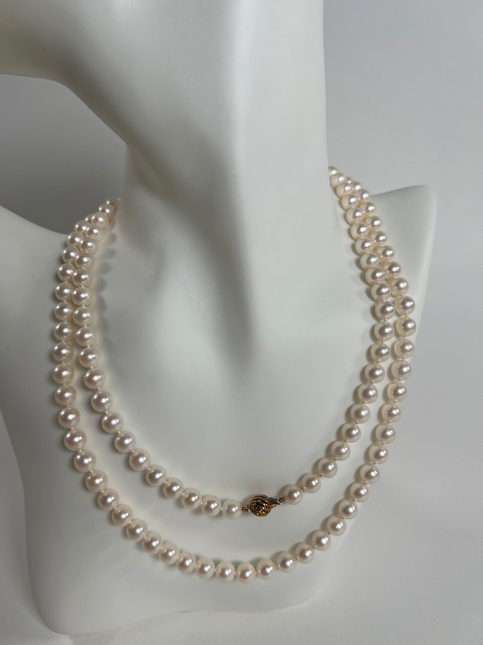Strand of Pearls with Gold Clasp: A strand of pearls, approximately 17.5 inches long when closed. Features a 14 karat gold clasp. Weighs approximately 2 oz.