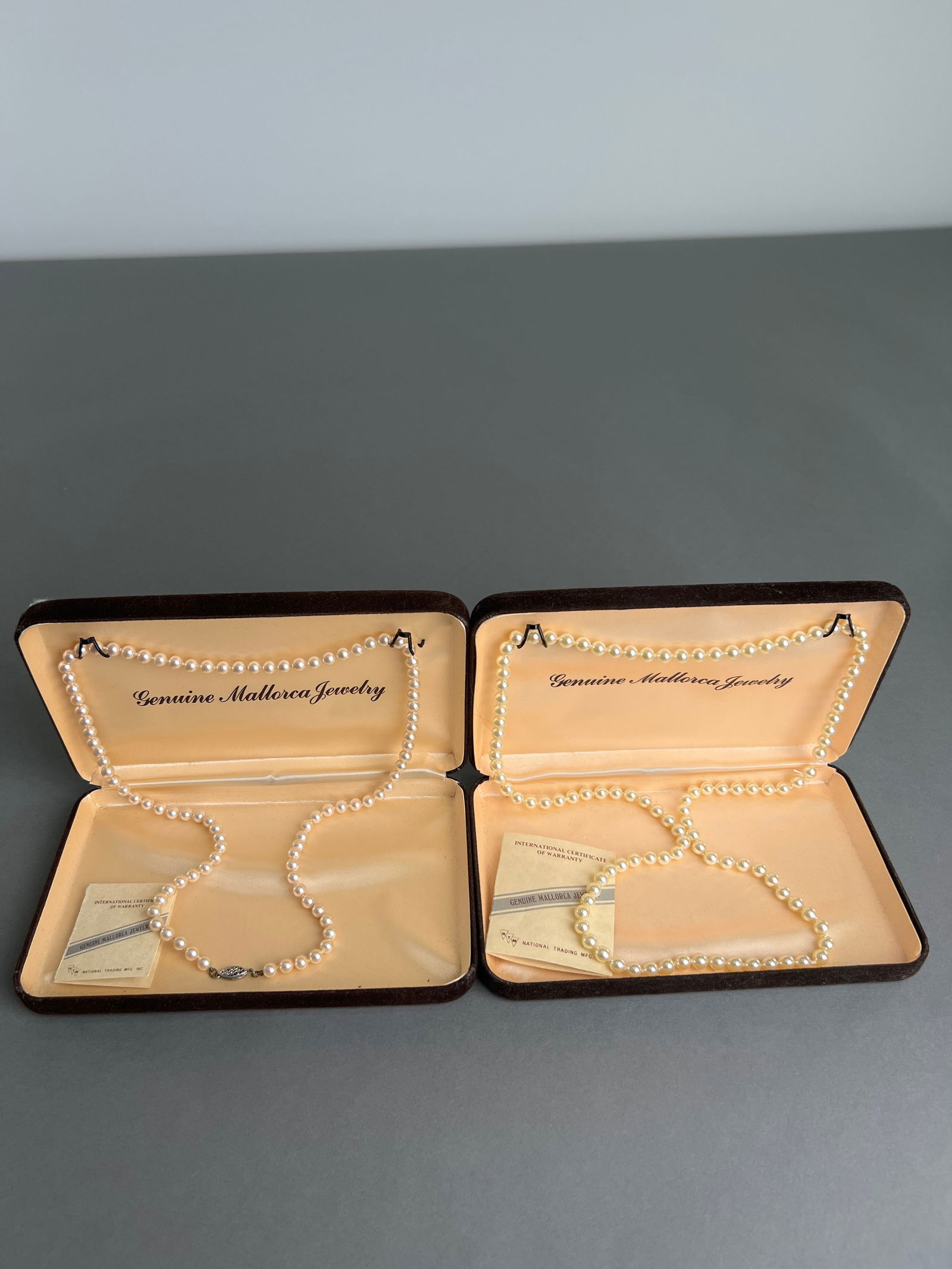 Two Genuine Mallorca Pearl Necklaces in Original Boxes: Two strands of genuine Mallorca pearls, presented in its original fitted boxes. The necklaces features a classic design with a secure clasp. A timeless piece of jewelry.Lengths : 15" , 12