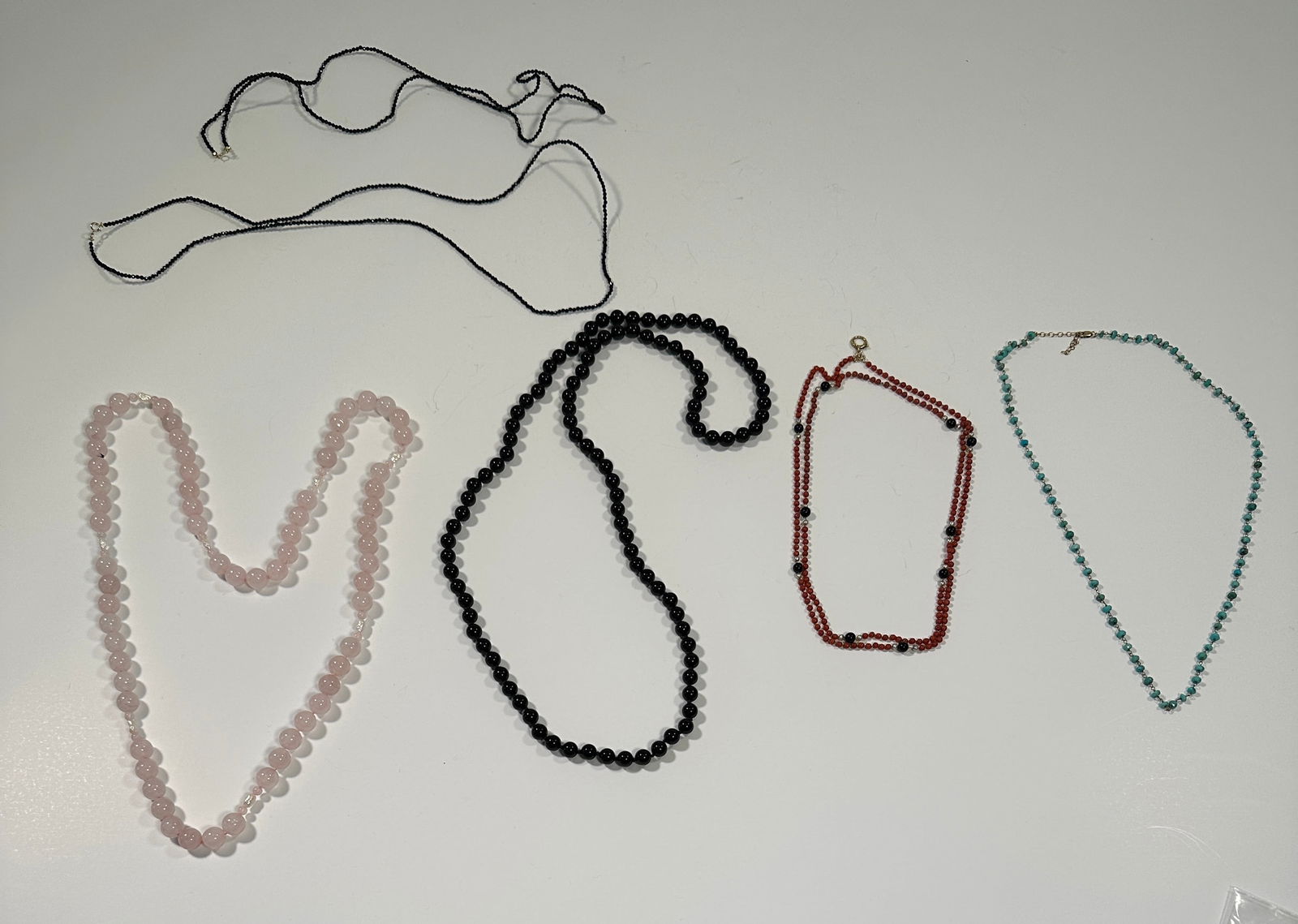 Group of Beaded Necklaces: Collection of beaded necklaces. Includes rose quartz, black onyx, coral, and turquoise examples. Longest necklace measures approximately 18 inches. Total weight: 7.2 oz.