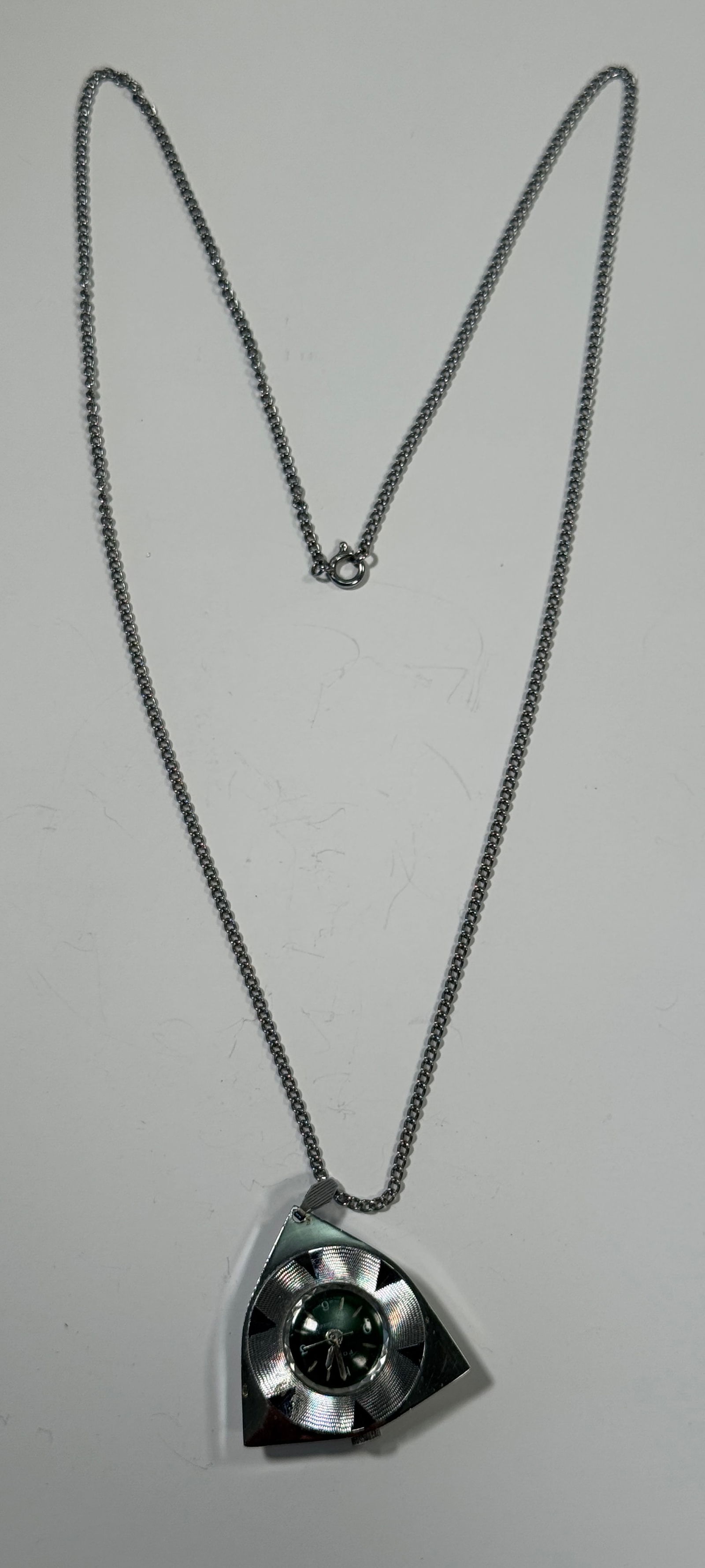 Focal Deluxe Pendant Watch Necklace: Focal Deluxe pendant watch necklace. The watch face is green and set in a silver tone, shield shaped pendant. The chain is silver tone. Swiss movement, Hong Kong dial. Not currently running, may need