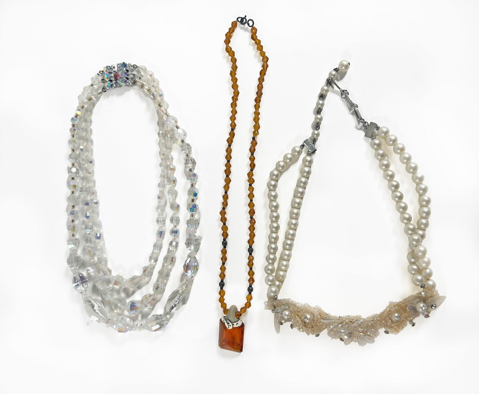 Vintage Beaded Necklace Trio: Three vintage necklaces. Includes a multi-strand crystal necklace, a faux pearl necklace marked "Coro" on the clasp, and a beaded amber-tone necklace. Total weight: 161.6g. Longest necklace