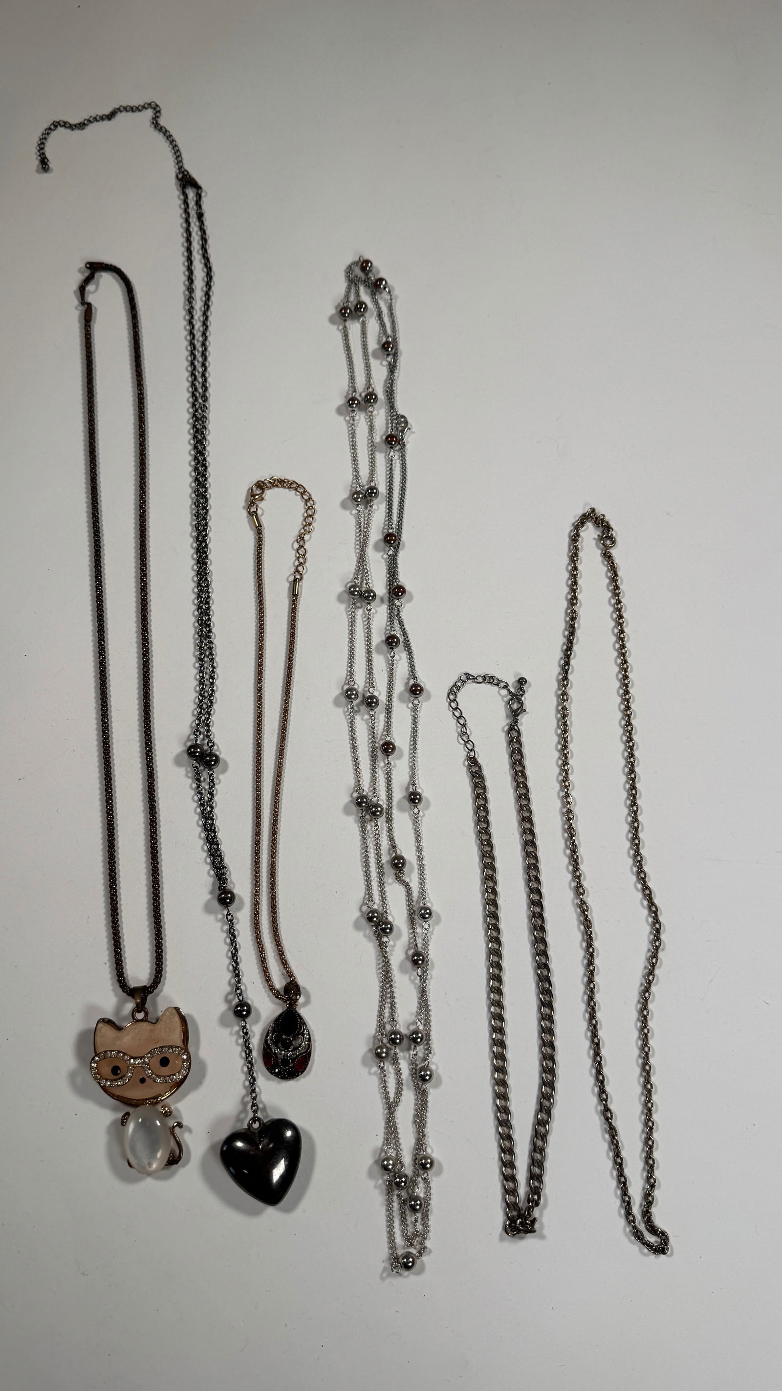 Group of Costume Necklaces: A collection of six costume necklaces featuring various pendants and chain styles. The longest measures approximately 23.5 inches. Total weight is 3.8 oz.