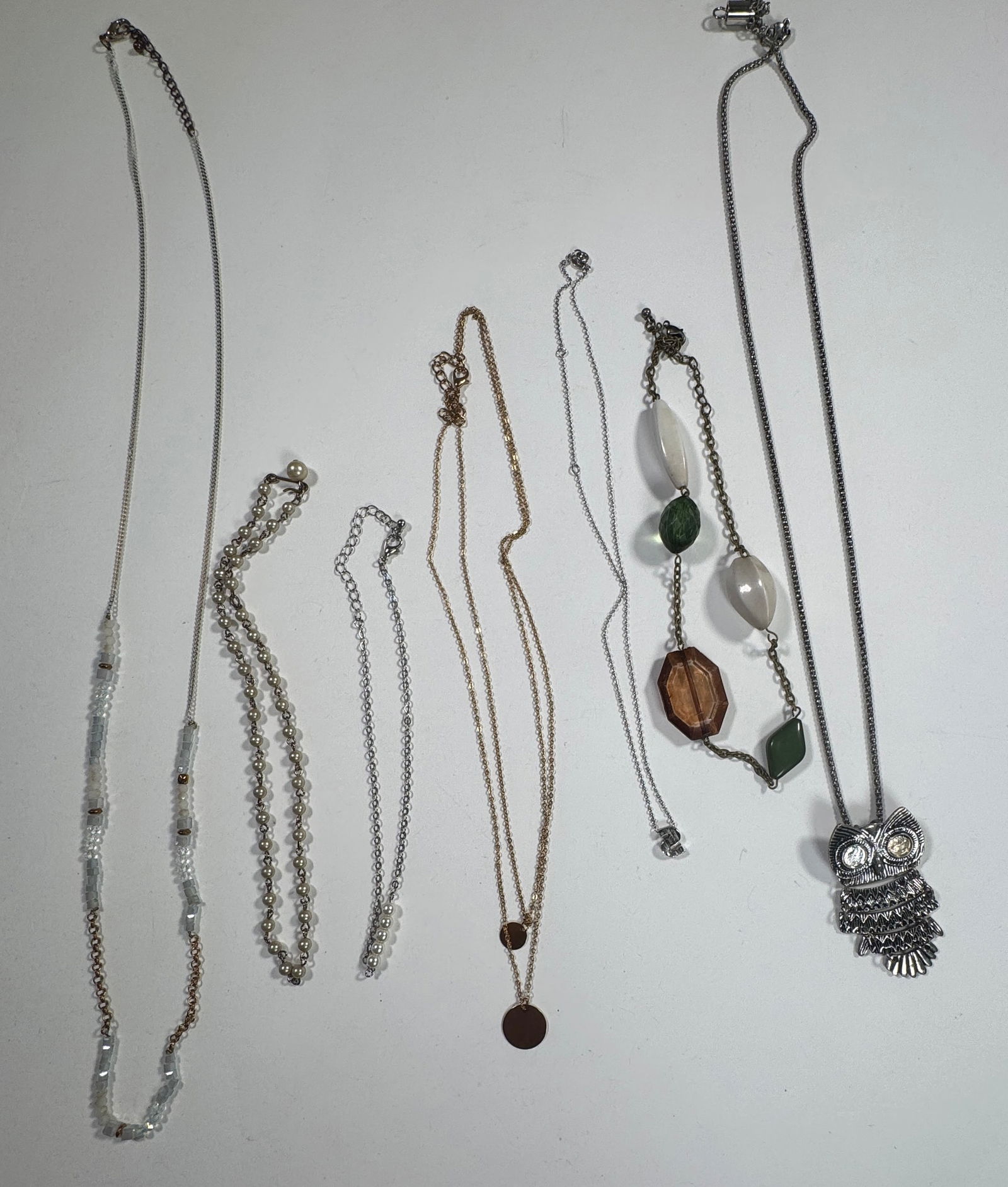 Group of Fashion Necklaces: Collection of seven fashion necklaces, including beaded, pendant, and chain styles. One owl pendant necklace is marked Avon. Longest necklace measures approximately 18.25 inches.