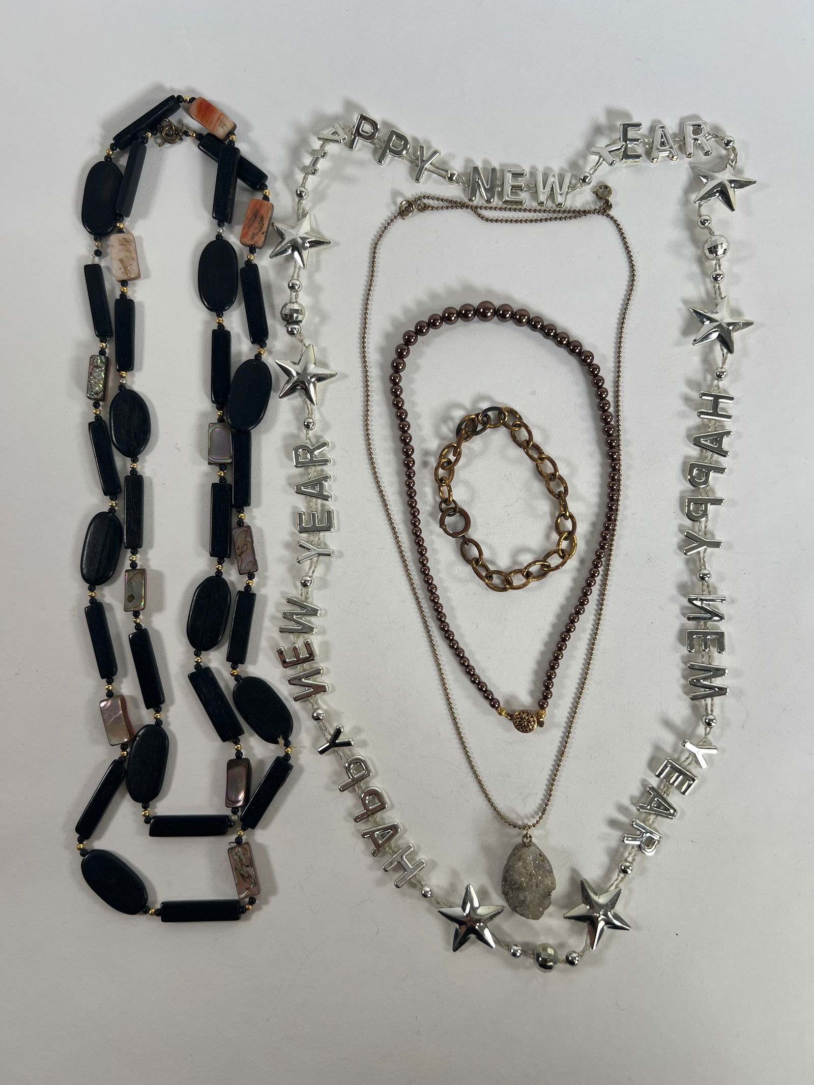 Assorted Costume Jewelry Lot: Necklaces & Bracelet: Lot of assorted costume jewelry including beaded necklaces, a 'Happy New Year' necklace, and a chain link bracelet. Lengths range from 6.5 to 27.25 inches. Total weight is 3.5 oz.