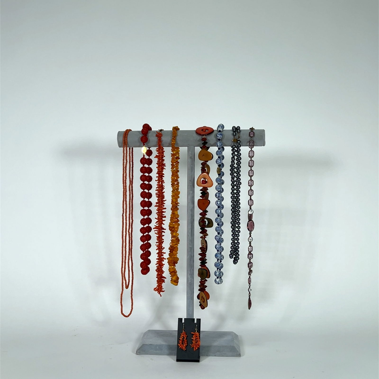 Assorted Beaded Necklace and Earring Collection: Collection of beaded necklaces and earrings in various colors and styles, including coral, amber, and blue and white porcelain style beads. Some necklaces are multi-strand. Earrings appear to match on