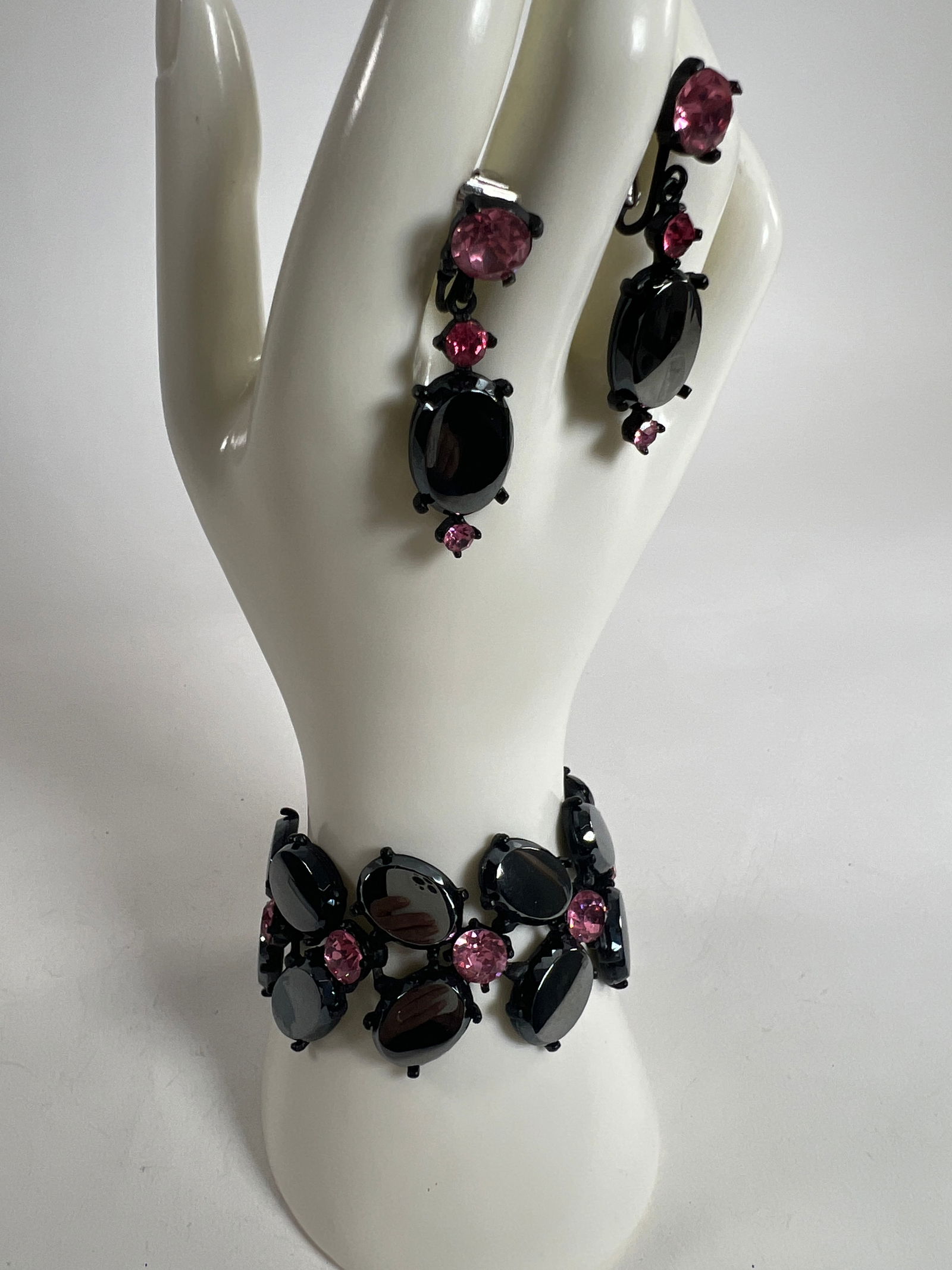 Black Tone Bracelet and Earring Set with Pink Accents: Black tone bracelet and earring set featuring black and pink stones. Bracelet measures approximately 1.25 x 3.5 inches. Weight: 3 oz.