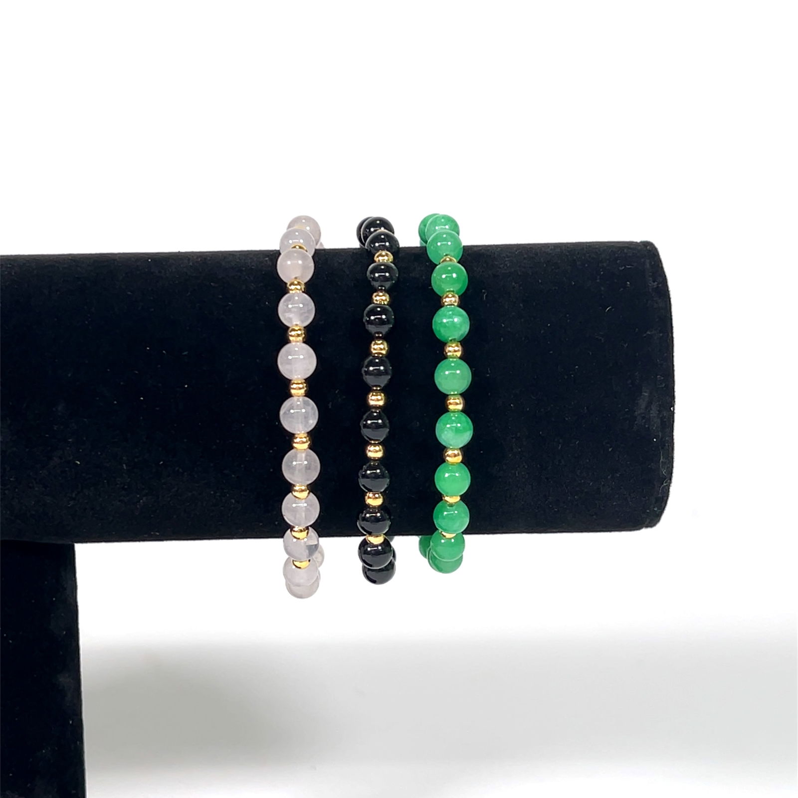 Set of Three Beaded Bracelets: Set of three beaded bracelets. One rose quartz, one black onyx, and one green jade. Each bracelet features gold-tone accents and a clasp closure.