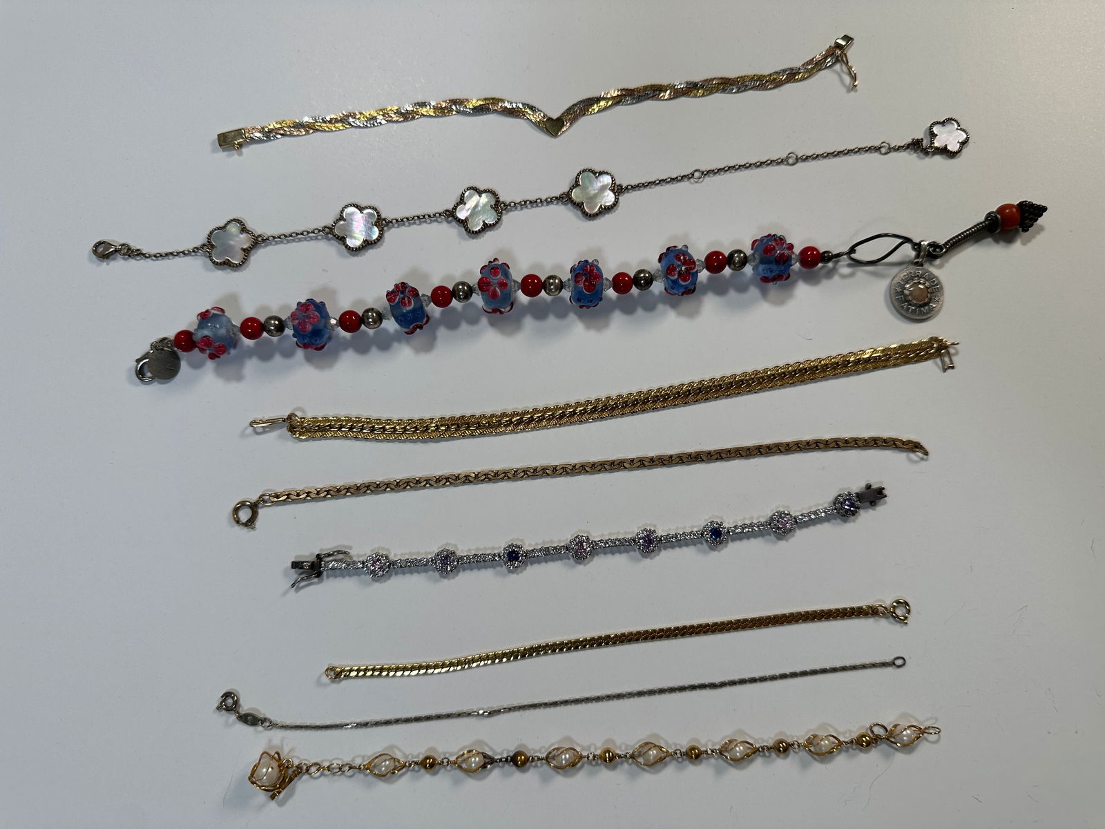 Group of Assorted Costume Bracelets (9): A collection of nine assorted costume bracelets, featuring various designs including beaded, chain, and decorative elements. Some bracelets appear to be gold or silver tone. See images for details.