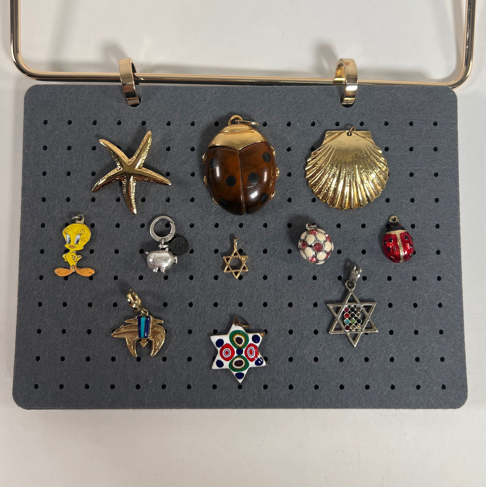 Collection of Eleven Costume Charms and Pendants: A collection of eleven costume charms and pendants, including a ladybug, starfish, shell, Tweety Bird, pig, several Star of David and more. The largest is approximately 2 inches long. Total weight: 3.