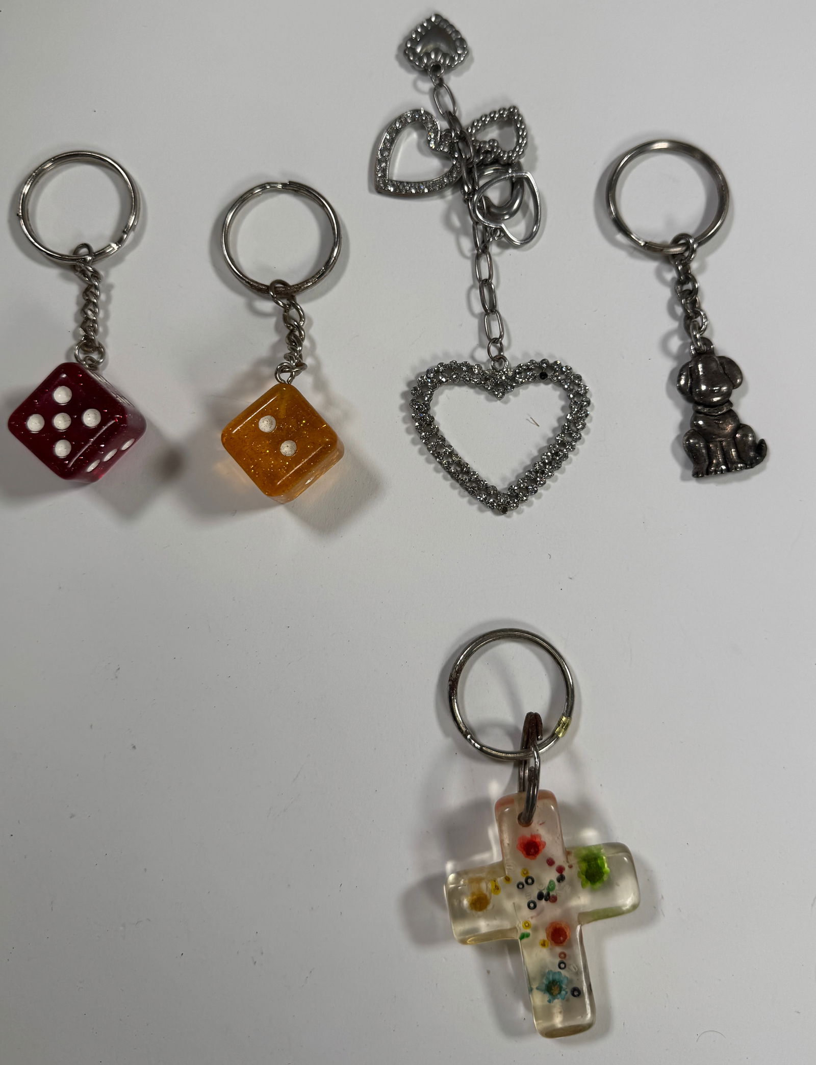 Group of Five Keychains: Group of five keychains, including dice, heart, dog, and cross designs. The largest measures 5.25 inches. Total weight: 3.6 oz.
