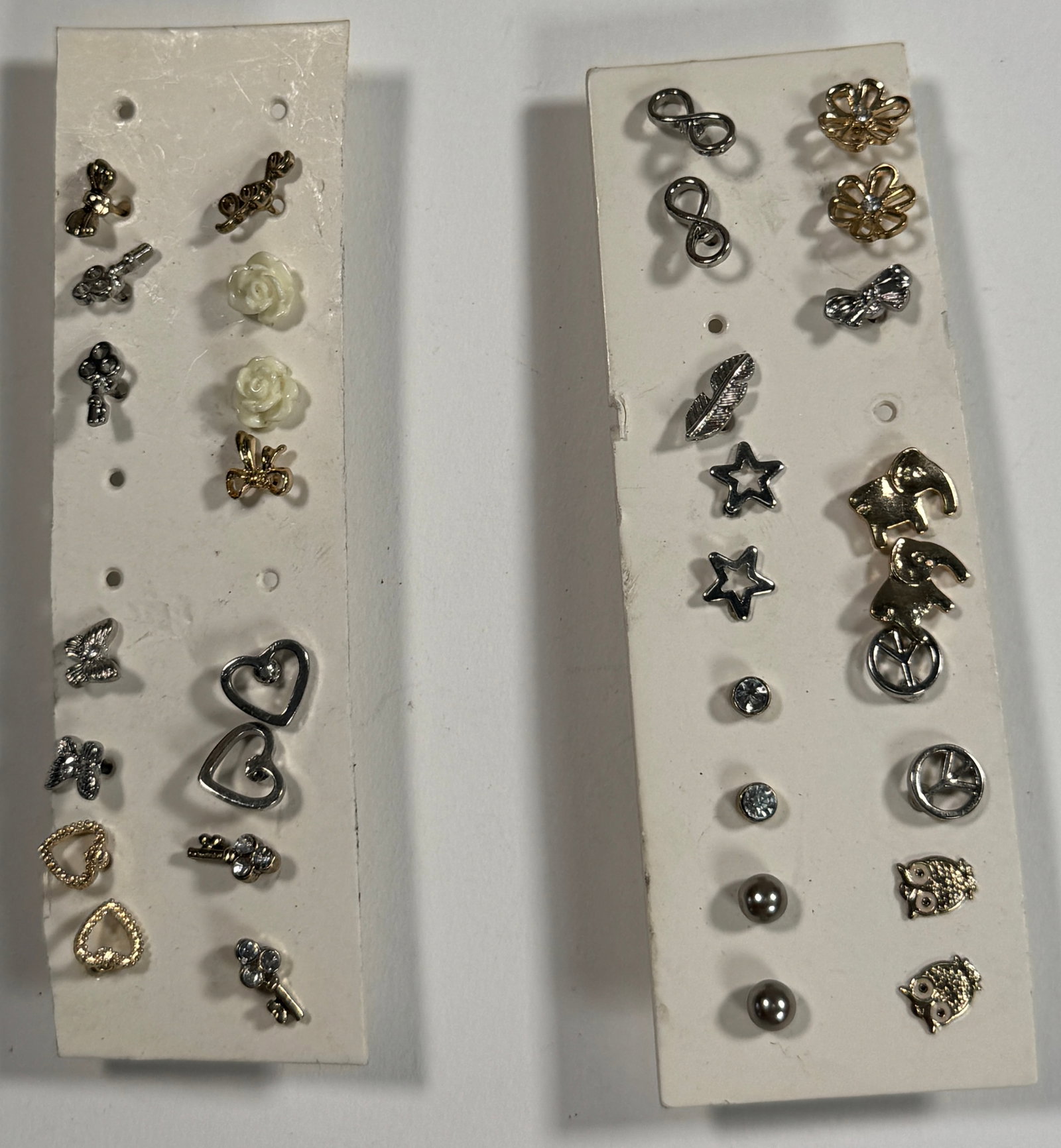 Two Cards of Assorted Stud Earrings: Two cards of assorted stud earrings in various shapes and colors. Includes hearts, stars, flowers, and geometric designs. Weight: 0.6 oz.