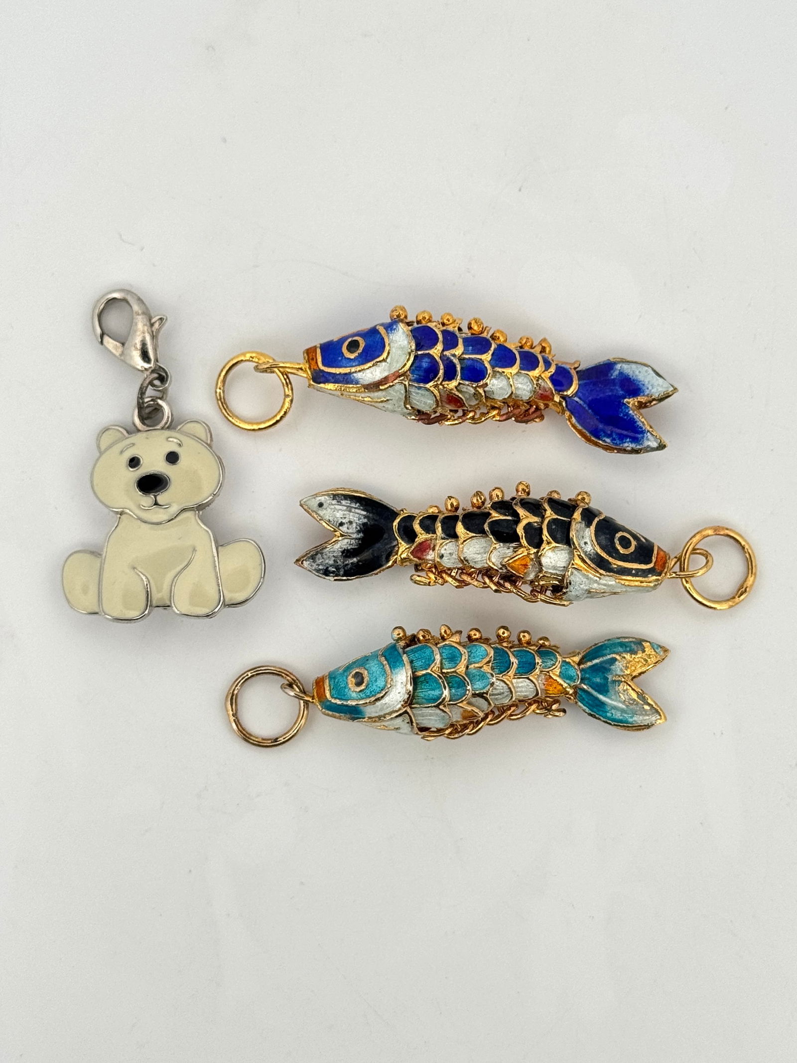 Enamel Fish and Bear Charms (4): Group of four charms including three colorful enamel fish charms and a white bear charm with lobster clasp. Good overall condition. Weight: 17.1g. Largest one: 2''. 