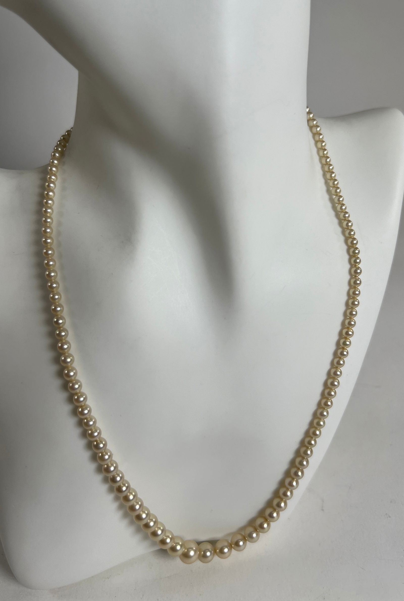 Vintage Graduated Faux Pearl Necklace: Vintage graduated faux pearl necklace. The necklace measures approximately 9.75 inches in length and weighs 0.5 oz. Features a decorative clasp with a 14 karat stamp.