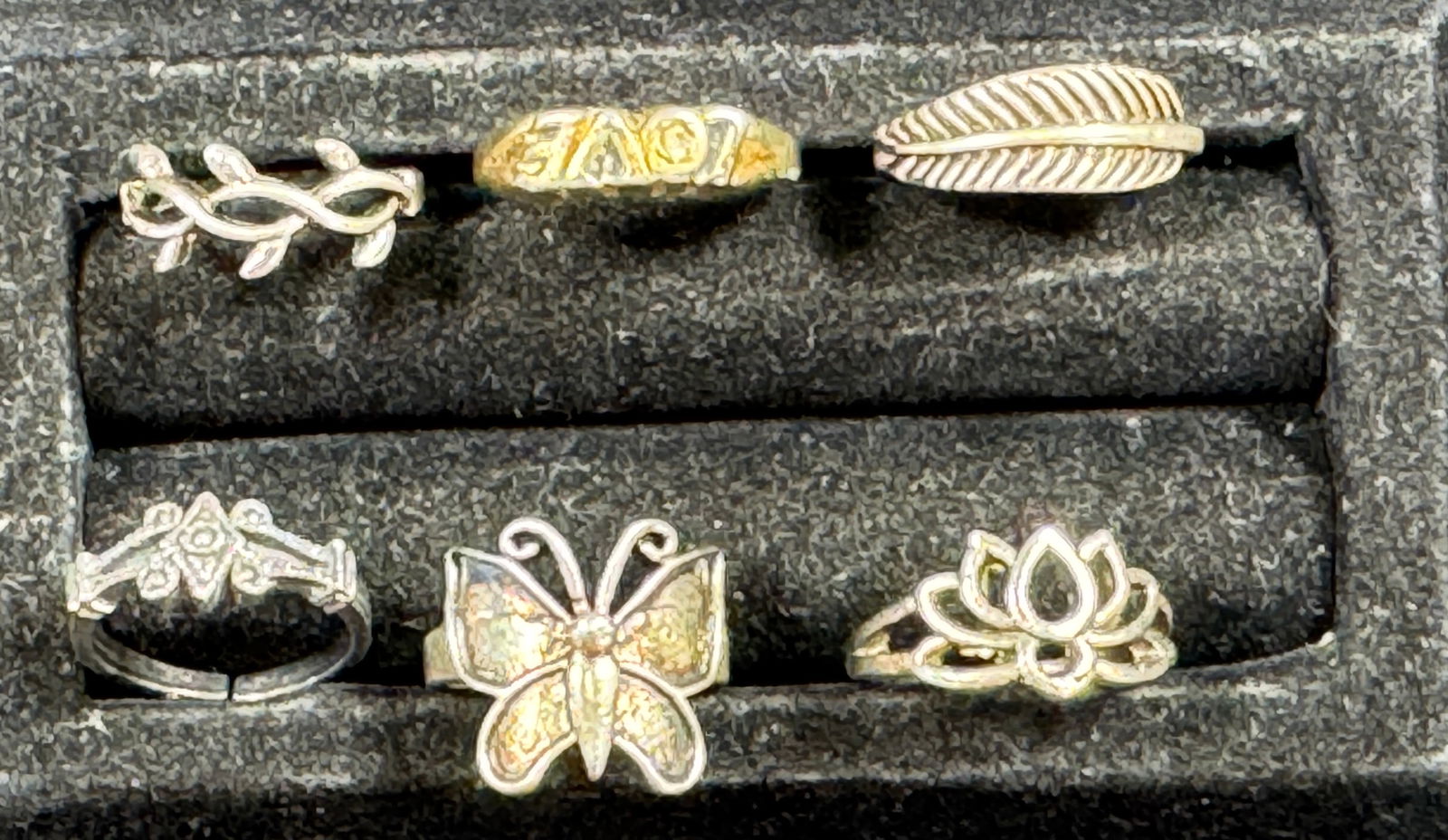 Six Assorted Fashion Rings: This lot features six assorted fashion rings. The rings are various sizes and designs, including floral, leaf, and butterfly motifs. Weight: 0.6 oz. Sizes: 5, 5.5, 7, 8.5, 6.5, 8.