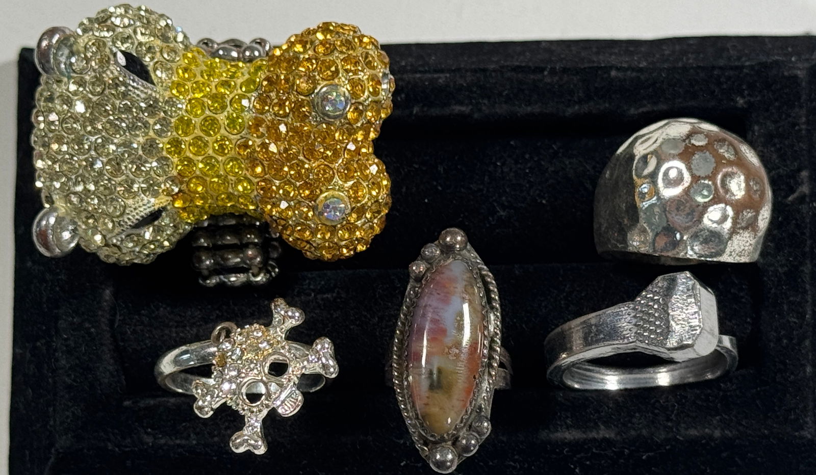 Group of Five Fashion Rings: Collection of five fashion rings, including a rhinestone-studded rhino, a skull and crossbones, and a stone-set ring. Weight: 2.5 oz.