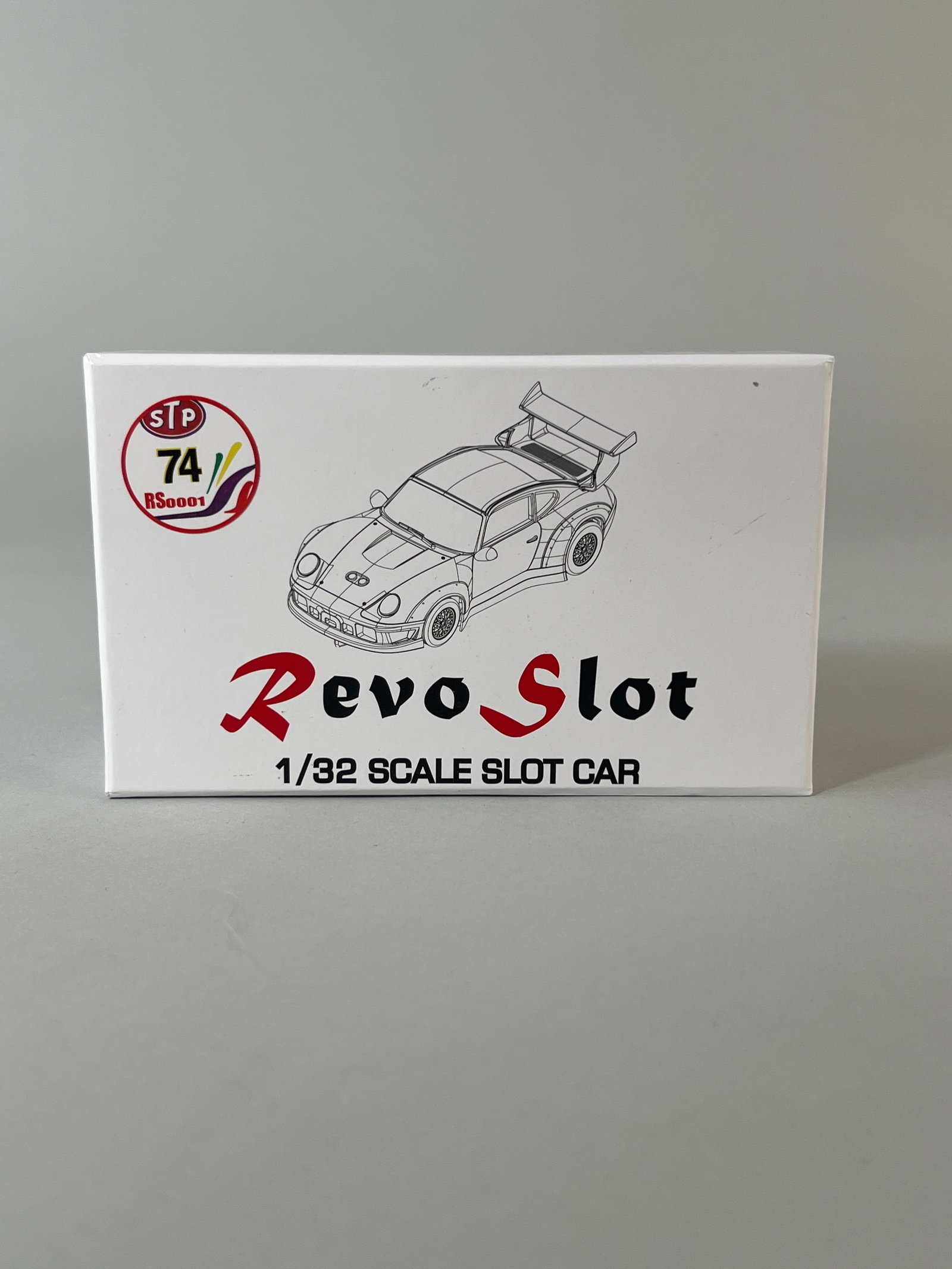 Revo Slot Porsche 911 GT1 #74 RS0001: A 1/32 scale slot car by Revo Slot, featuring a white Porsche 911 GT1 livery with STP and Exxon branding, and racing number 74. The car is presented in its original box. Weight: 10oz. Dimensions: