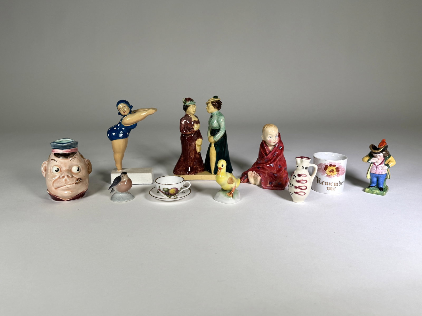 Collection of Figurines and Decorative Items: Group of ten assorted figures including a French Majolica "Wee Man" jug, a mid-century "swimming lady" figurine labeled "Peter Martin Original", a Royal Doulton "Thi