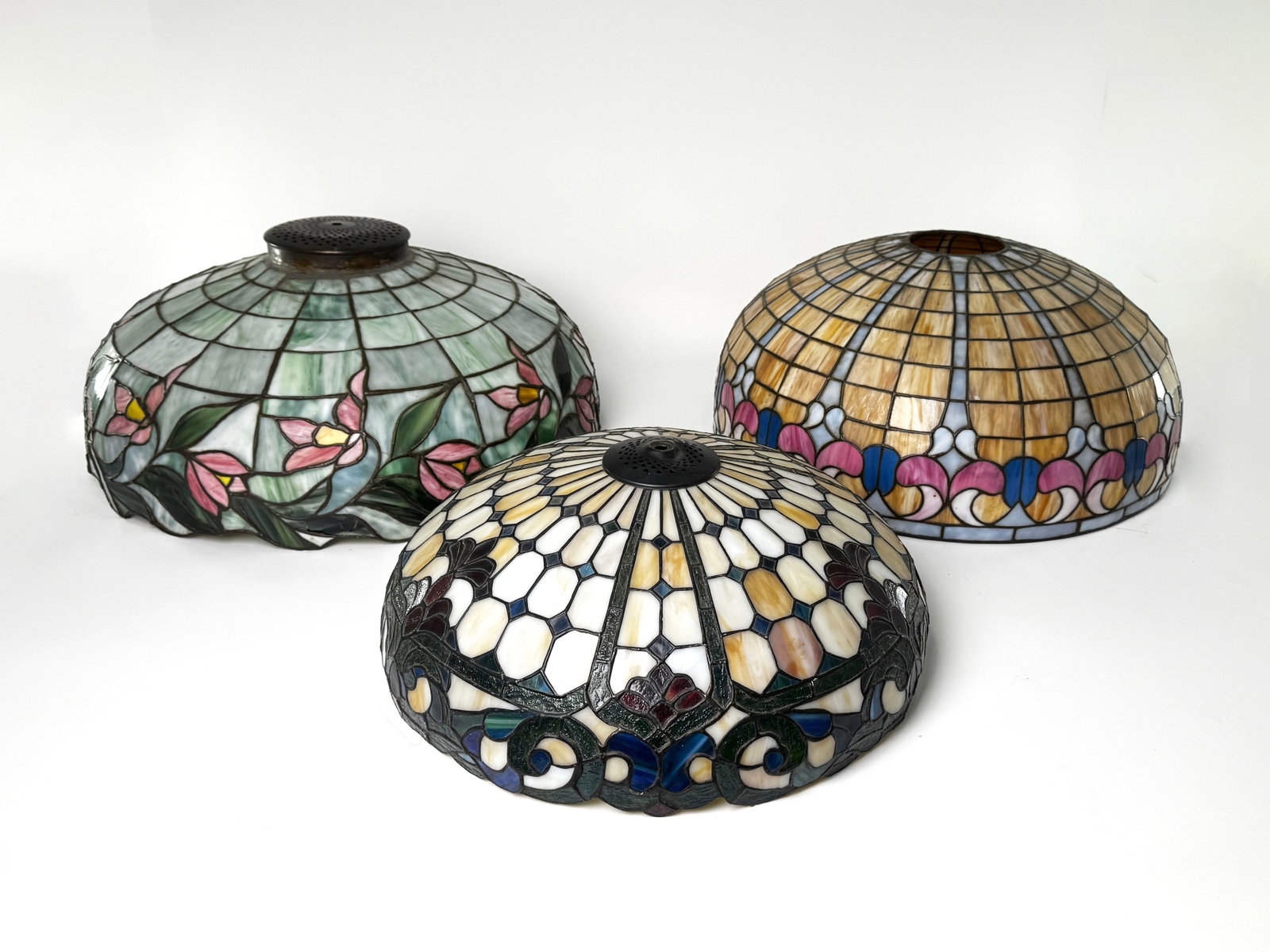Three Stained Glass Lamp Shades: Three stained glass lamp shades. One green with pink flowers (22 3/4" diameter, 11.5 lbs), one beige with dark green (18 1/4" diameter, 7 lbs), and one yellow/pink/blue (21 5/8"