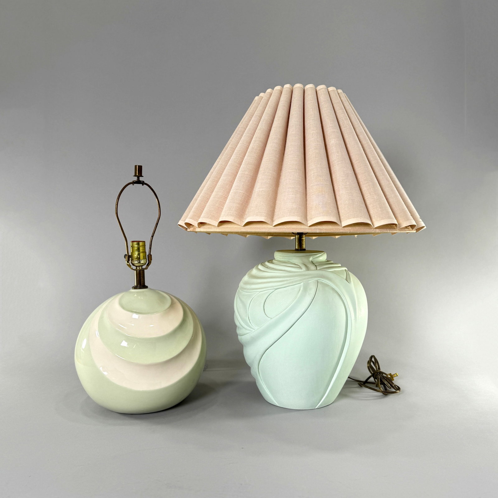 Two Mid-Century Modern Table Lamps: Two mid-century modern table lamps featuring drapery-like designs. One lamp is ceramic with concentric curves on a green background, and the other has a plaster base with a mint green finish. 