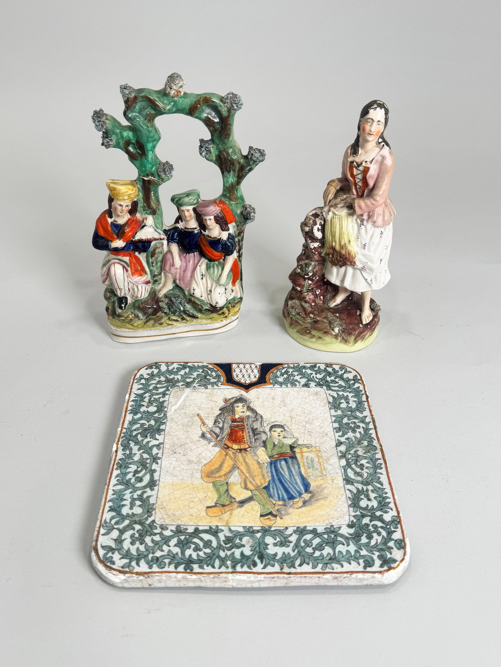 Three Antique Staffordshire Pottery Figures: Two Staffordshire pottery figures and one tile. Weight: 4lb 13oz. Largest: 5 1/2'' x 2 1/4'' x 9 3/4''.
