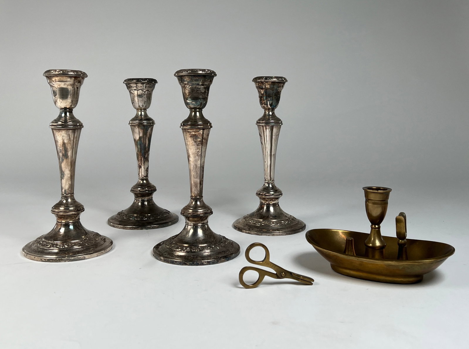 Silver-plate Candlestick Set with Brass Snuffer: Four silver-plate candlesticks, a brass snuffer, and wick trimmers. The Candlestick Dimensions: 4 3/8" x 4 3/8" x 9 1/8" Total weight: 7.15 lb