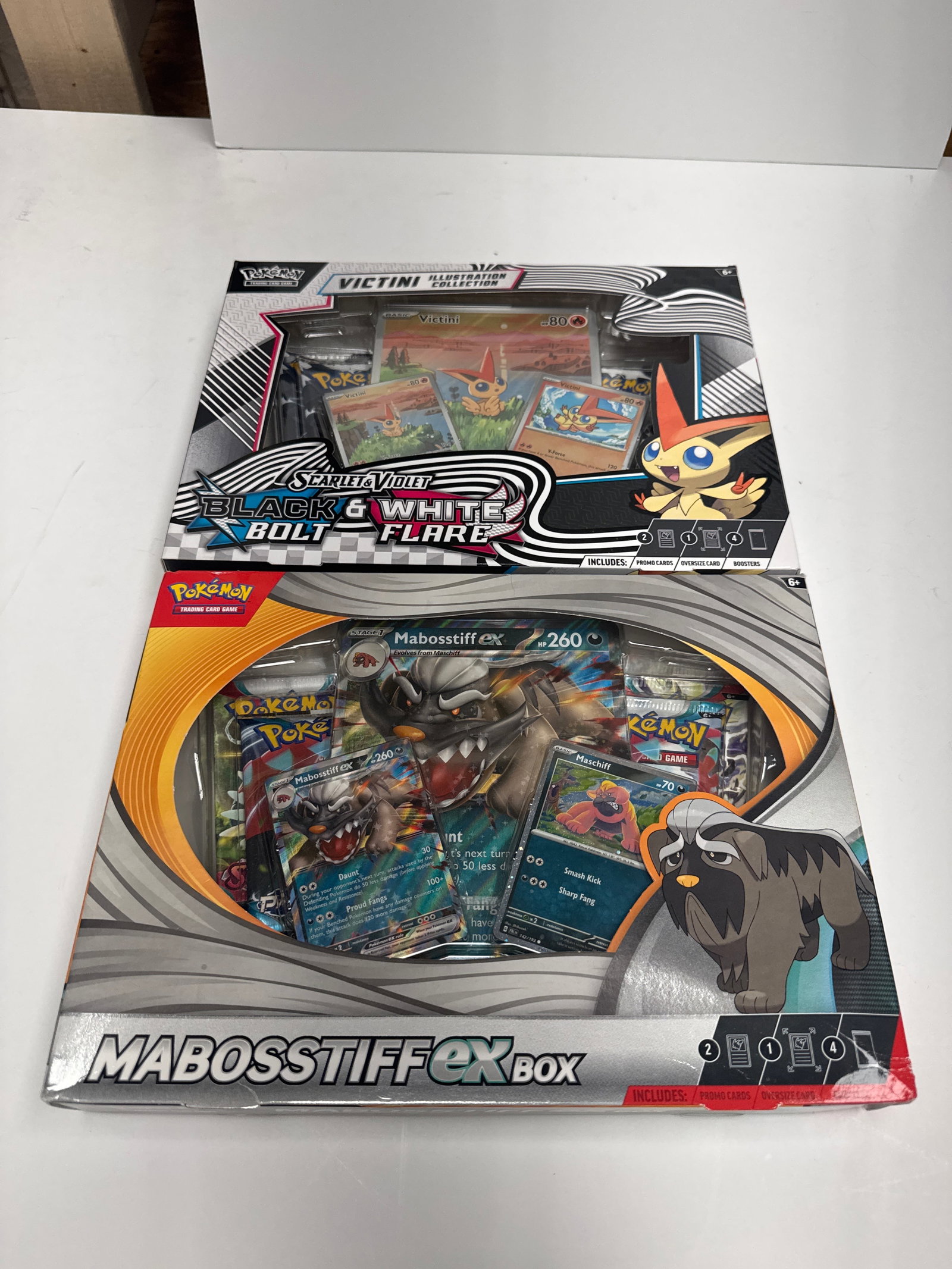 Pokemon TCG Scarlet & Violet Victini Illustration Collection & MABOSSTIFF EX Box: This lot includes two Pokemon Trading Card Game boxes: the Scarlet & Violet Victini Illustration Collection and the MABOSSTIFF EX Box. The Victini box features a full-art promo card, oversized promo c
