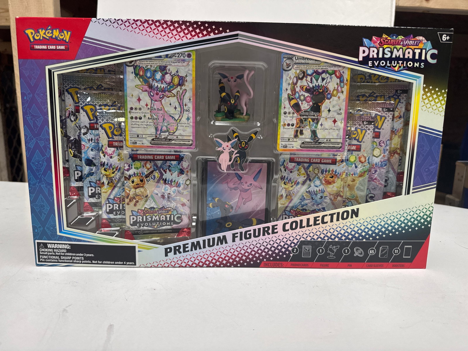 Pokemon Scarlet & Violet Prismatic Evolutions Premium Figure Collection: This collection features the Sun and Moon PokÃ©mon Espeon and Umbreon. It includes 65 card sleeves, 2 etched foil promo cards, 1 figure featuring Espeon and Umbreon, 1 pin, and 11 booster packs from