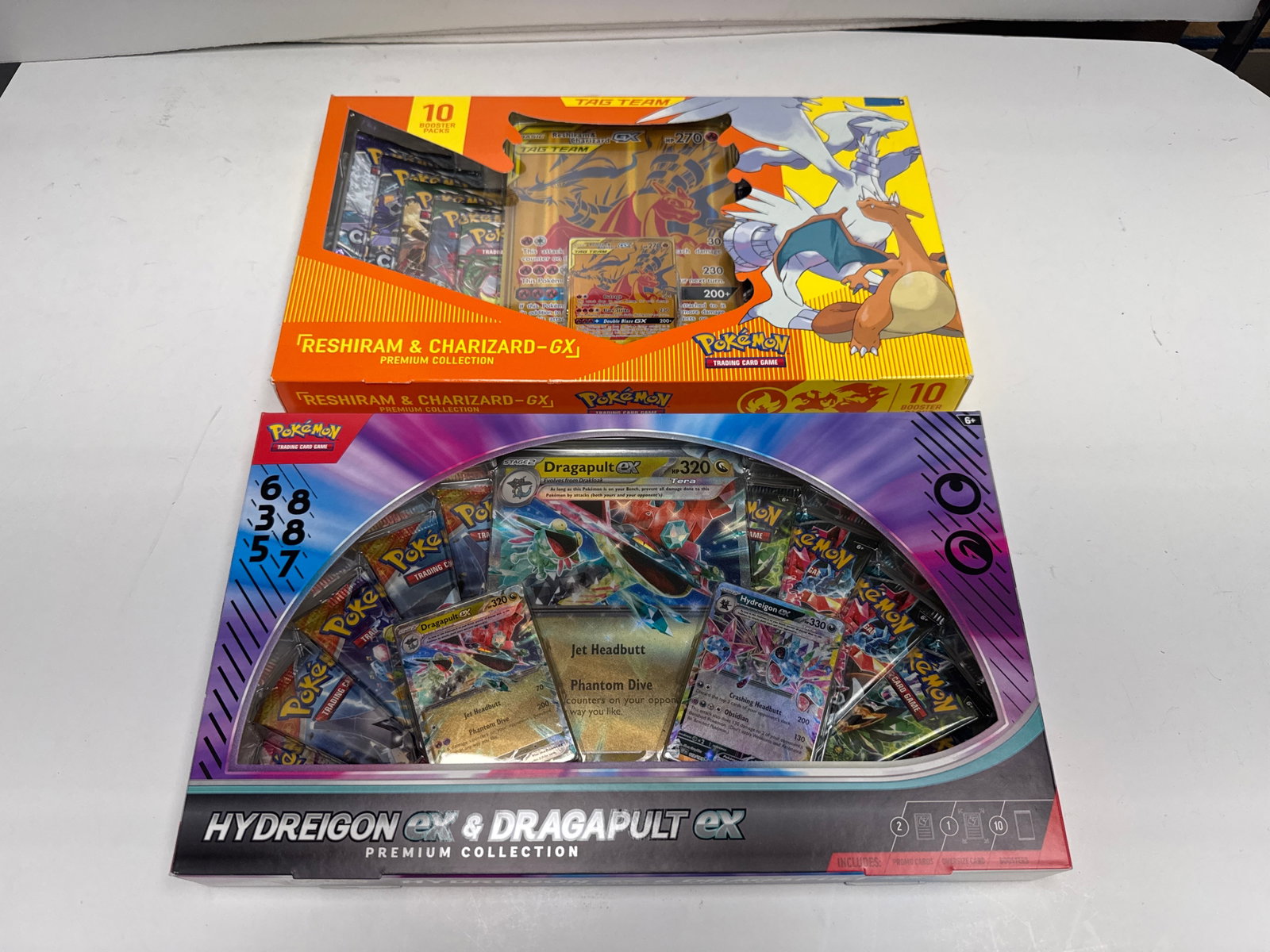 Pokemon TCG Premium Collections: Reshiram & Charizard-GX and Hydreigon EX & Dragapult EX: This lot features two Pokemon Trading Card Game Premium Collections: the Reshiram & Charizard-GX collection and the Hydreigon EX & Dragapult EX collection. Both collections include booster packs and p