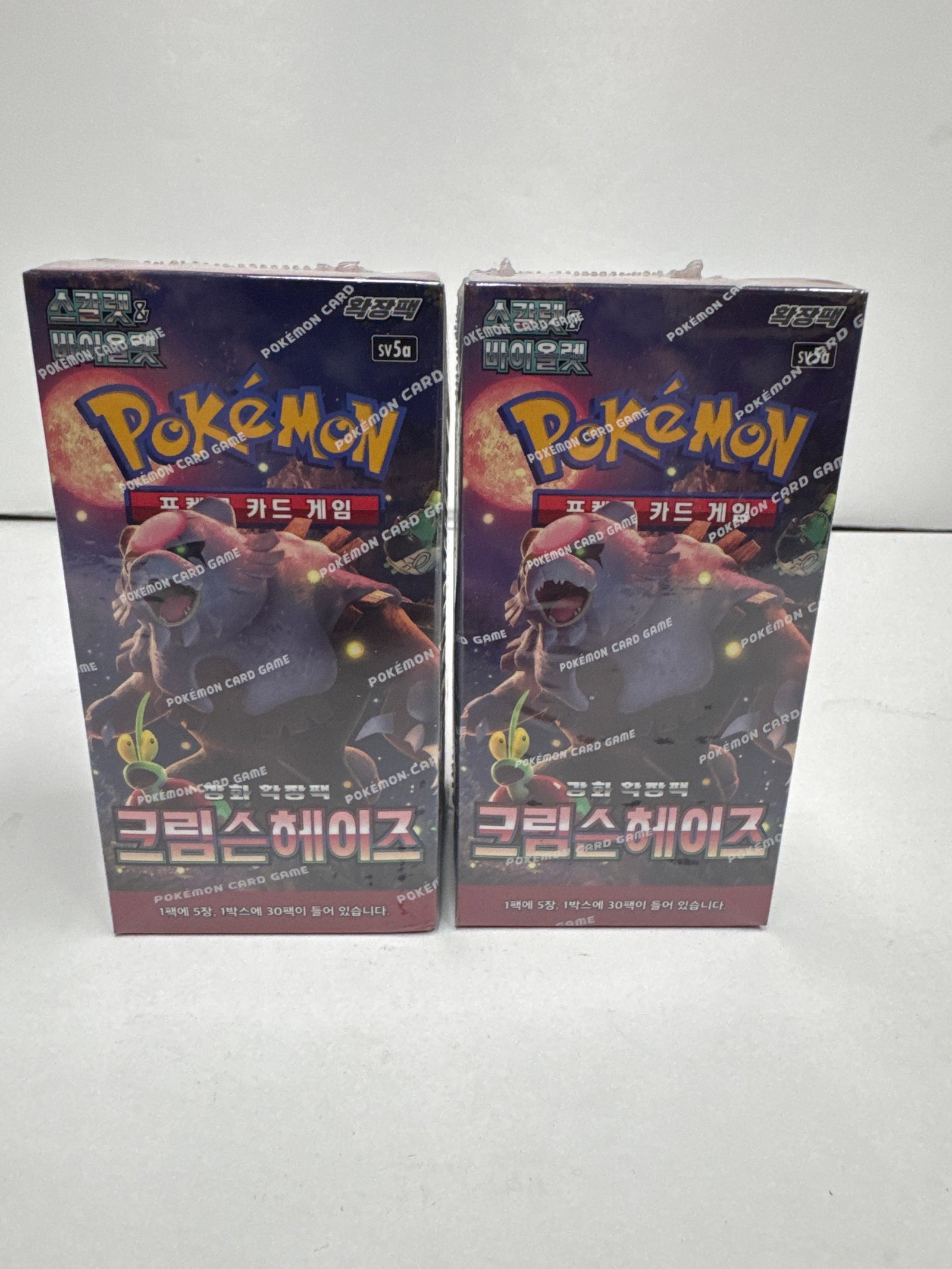 Two Pokemon Card Game Korean Booster Boxes - Crimson Haze: This lot features two sealed booster boxes of the Pokemon Card Game, specifically the Korean set 'Crimson Haze'. Each box contains 1 pack with 5 cards, and 30 packs in total. The boxes are in good con